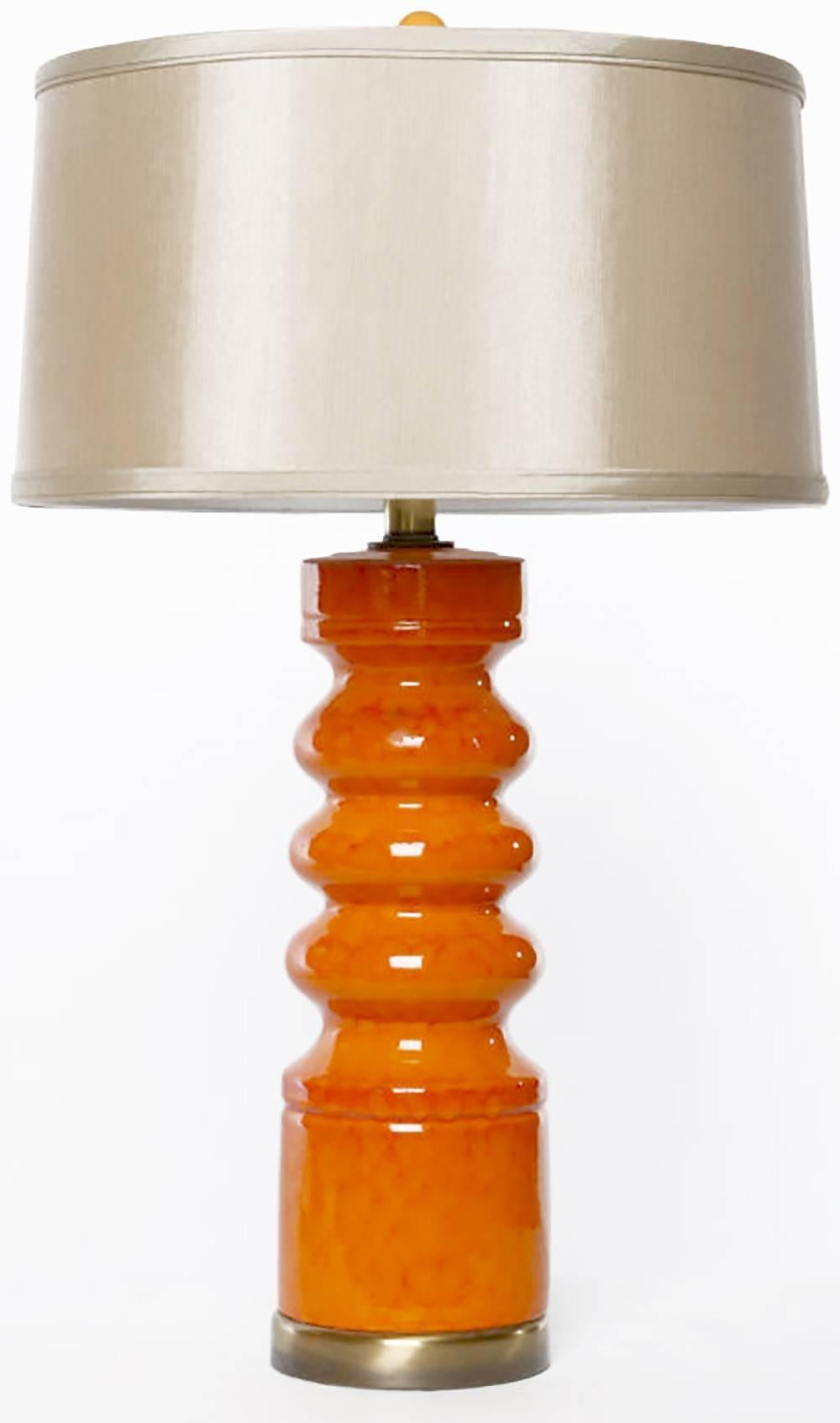 Pair of tangerine orange ceramic table lamps with a textured drip-glaze finish. Antiqued brass bases and stems. Brass harp and socket. Sold sans shades.