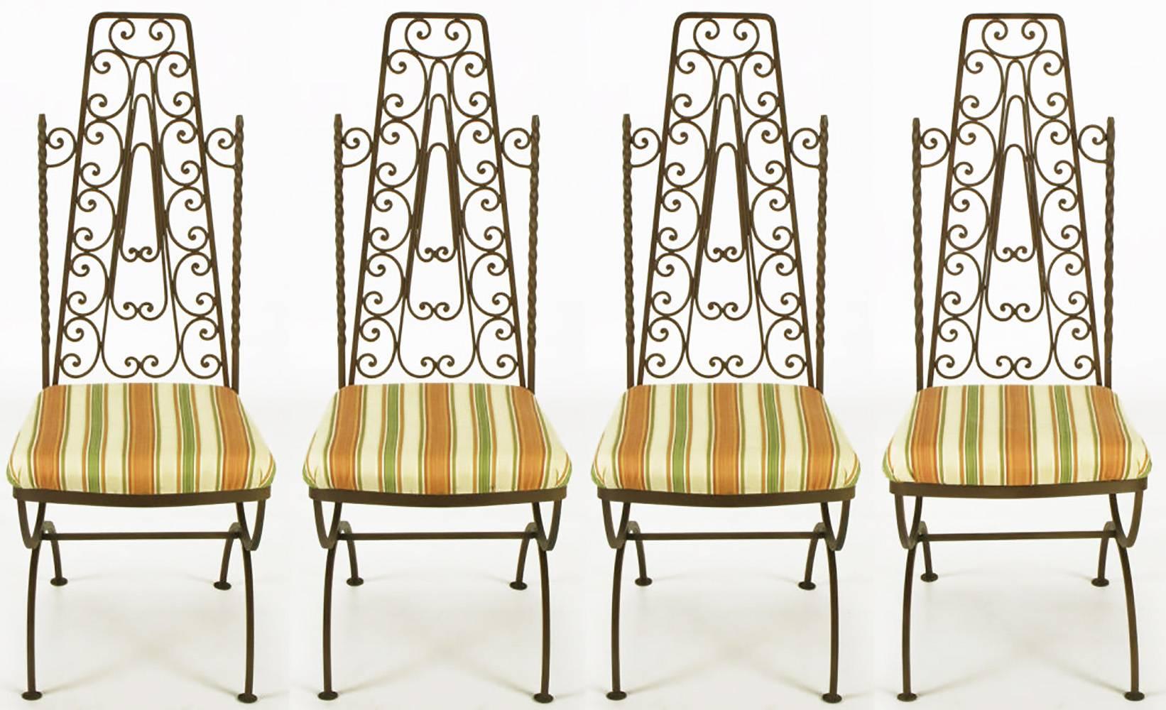 Spanish revival style hand-wrought iron, dark chocolate lacquered dining chairs. Twisted and filigreed open iron backs with fixed seat cushions upholstered in a striped silk of olive, peach and cream. Curule form legs with center stretchers. Could