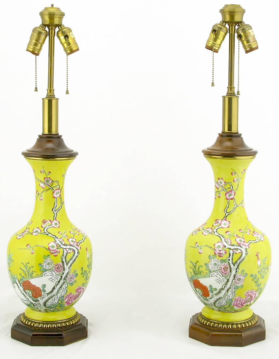 Vase form chinoiserie table lamps by Paul Hanson. The bodies are comprised of a vibrant yellow glazed ceramic vase with hand painted floral detail. The base is carved wood, with gilt egg detail. Cap is also carved wood over a brass neck. Adjustable