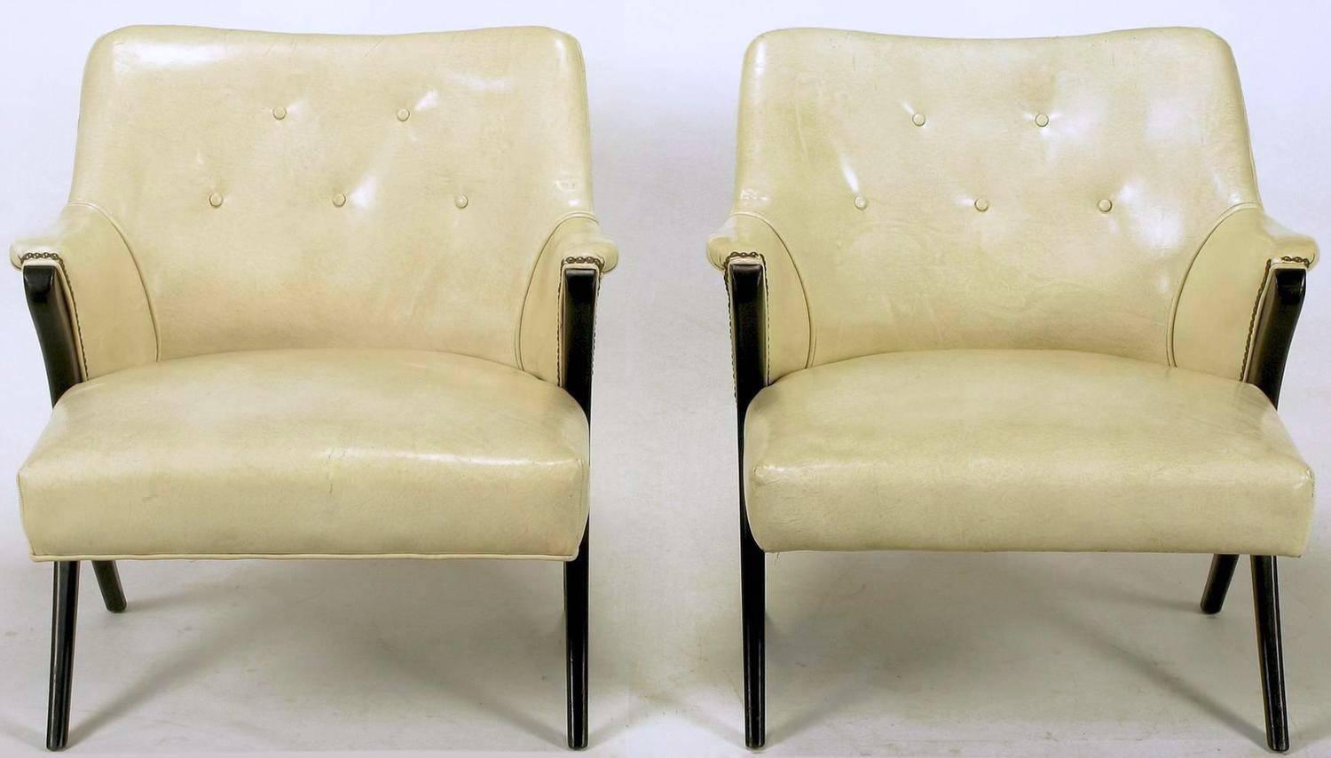 Pair of 1940s modernist club chairs in original bone glazed leather upholstery. Ebonized mahogany arms and legs in a distinctive Y shape. Brass nailhead accents. One chair has bottom welt and one does not. Possibly the inspiration for the Karpen Co.