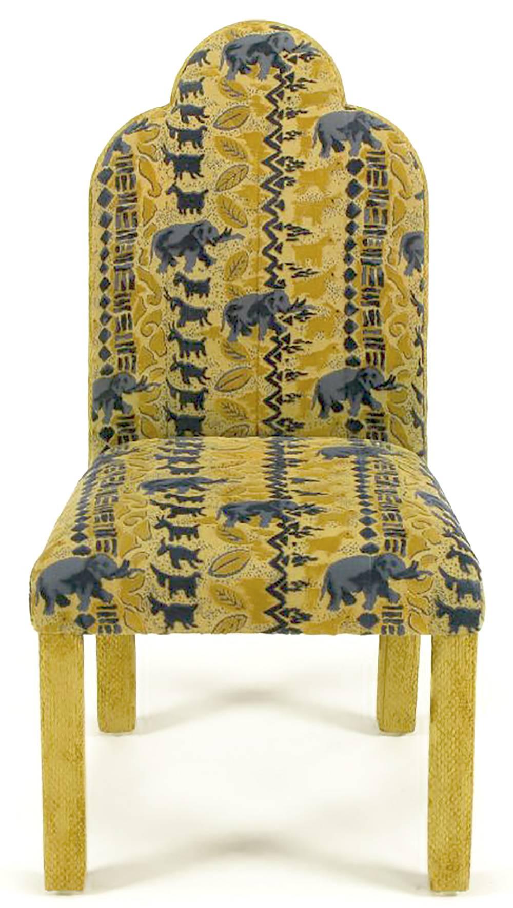 Set of four game or dining table triple arch back deco revival fully upholstered side chairs. Cover in gold, saffron and blue print chenille fabric, with African inspired characters, such as elephants, ibix and patterns. Sold with set of seven