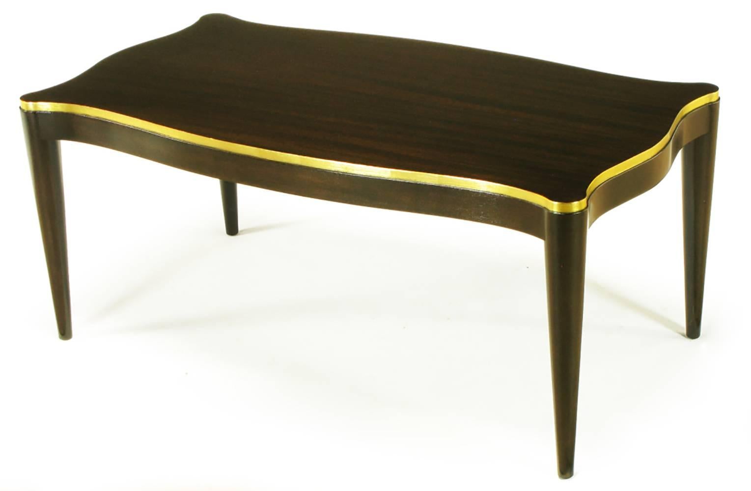Davidson Ltd, elegant ribbon mahogany and parcel gilt sinuous coffee table, Extreme taper to the conical legs form following apron with gilt banding. Davidson Ltd. was a custom Chicago fine furniture maker that sold exclusively to the trade. Partial