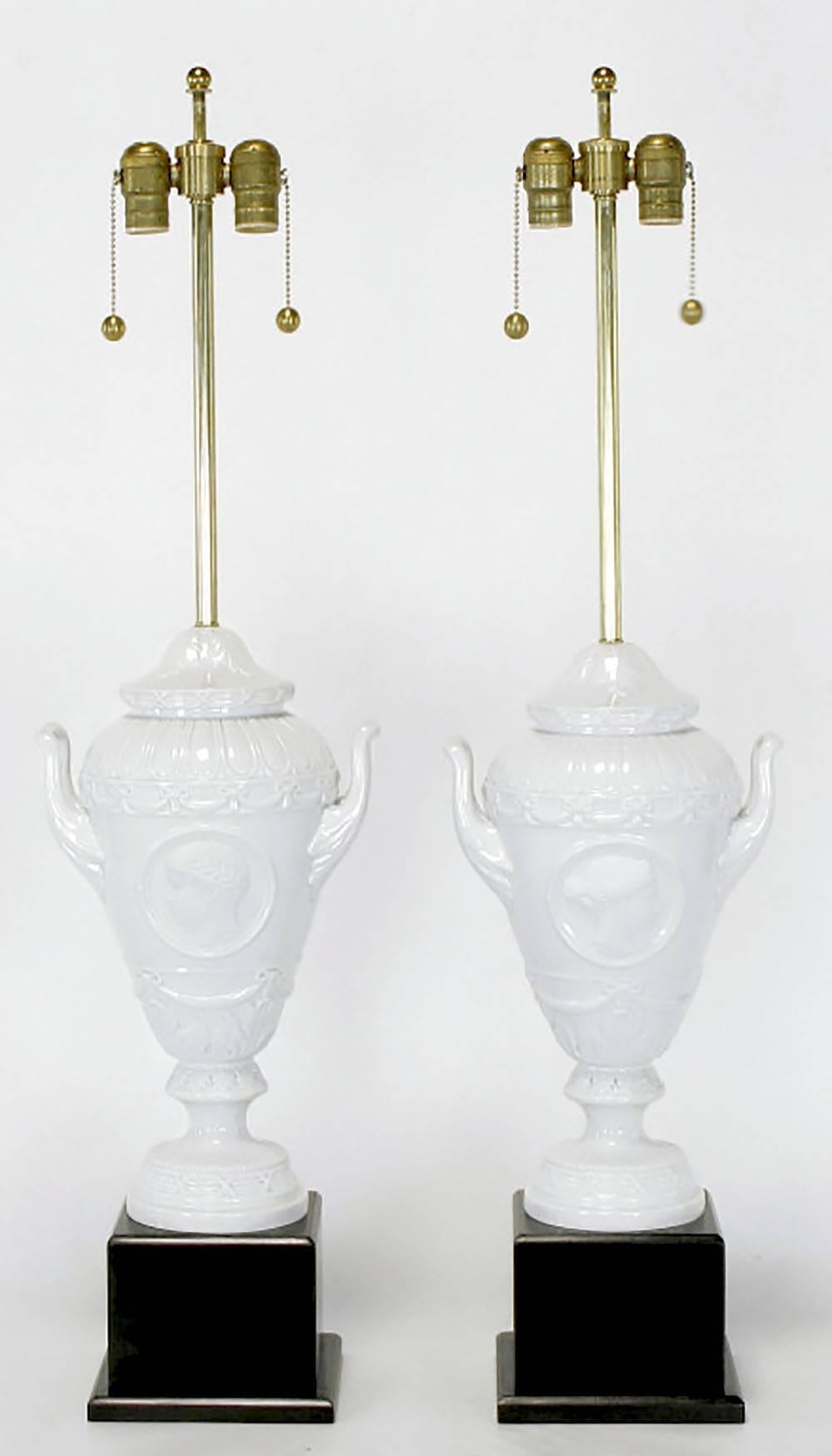 Fine pair of white German porcelain urn form table lamps with black lacquered wood plinth bases. Urn body is comprised of three parts with the flanged base, handled urn body, and bell shaped top being a separate pieces. Brass stem and Dual socket