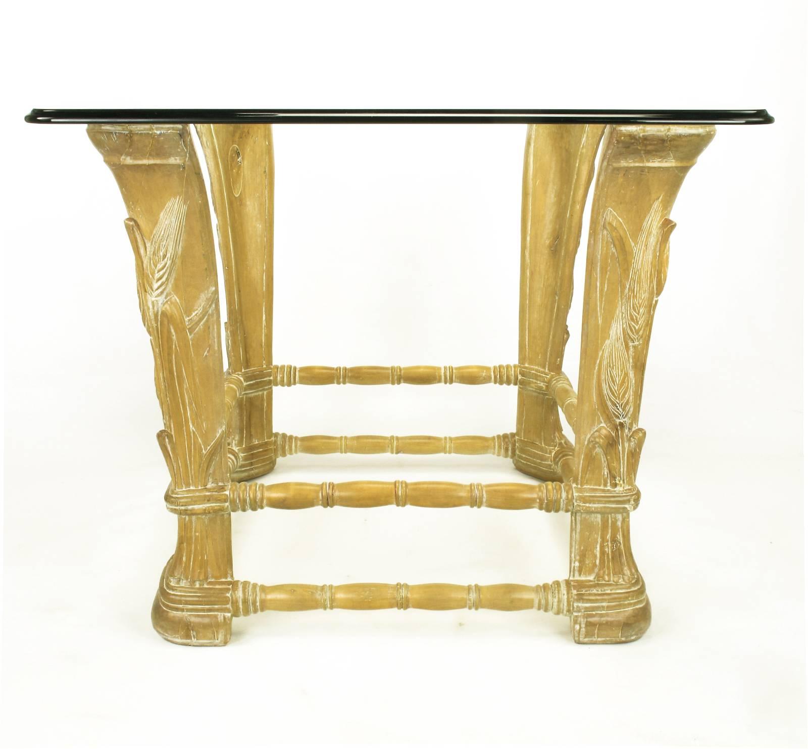 Tavolo centrale in legno di ontano calcinato in stile francese con grano intagliato in rilievo. Quattro montanti intagliati con doppie barelle segmentate che collegano ogni gamba. Piano in vetro quadrato con bordo smussato e spessore di 3/4