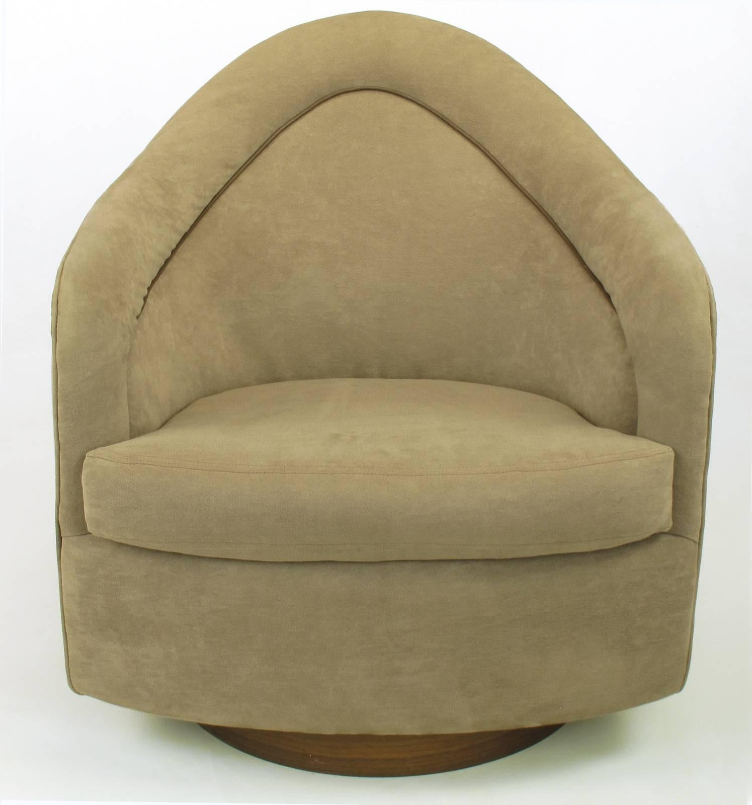 Pair of Milo Baughman for Thayer Coggin swiveling club chairs with round walnut plinth bases and tear drop back. Taupe ultra suede upholstery with brown leather like welting.