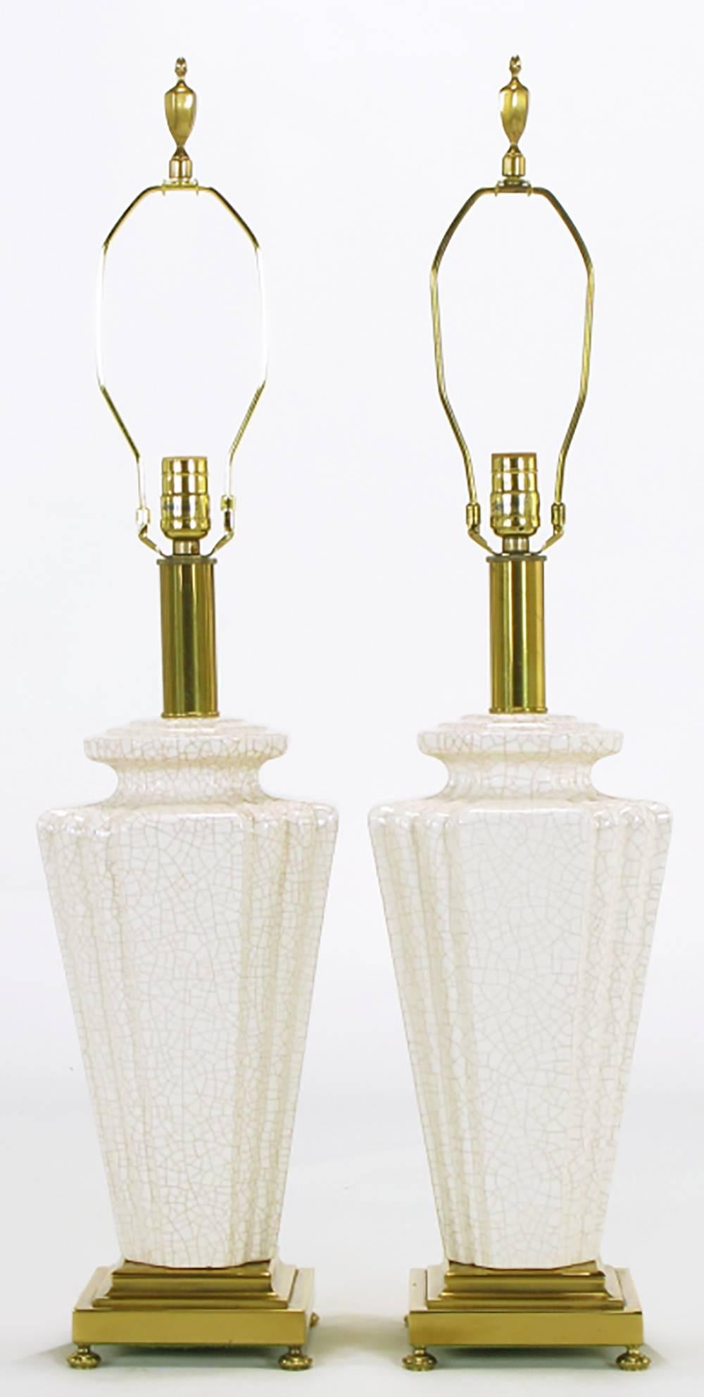 Elegant Rembrandt lamp company table lamps with ceramic bodies in urn-form, with stepped-back corners, finished in an off-white craquelure glaze. The base is finished in brass, with brass bun feet. Original finials. Sold sans shades.