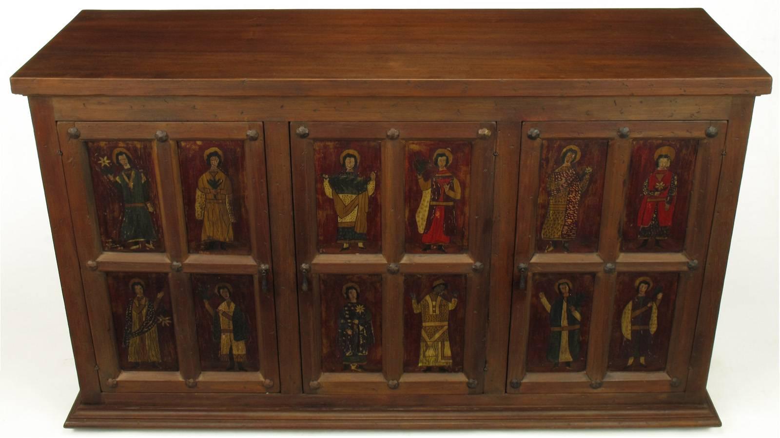 An adaptation of a 16th century hand constructed distressed pine cabinet. The retablo panels depicting the 12 apostles are hand-painted in polychrome over gold leaf. The three-door open via hand-forged iron drop pulls with hand-forged iron rosette