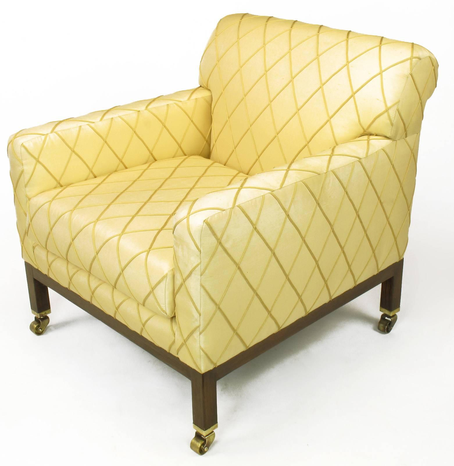Edward Wormley for Dunbar club chair with rolled back, ash wood Parsons style legs with solid brass sabots and castors. Older saffron silk upholstery with embroidered harlequin pattern in very good condition. Second matching chair in need of