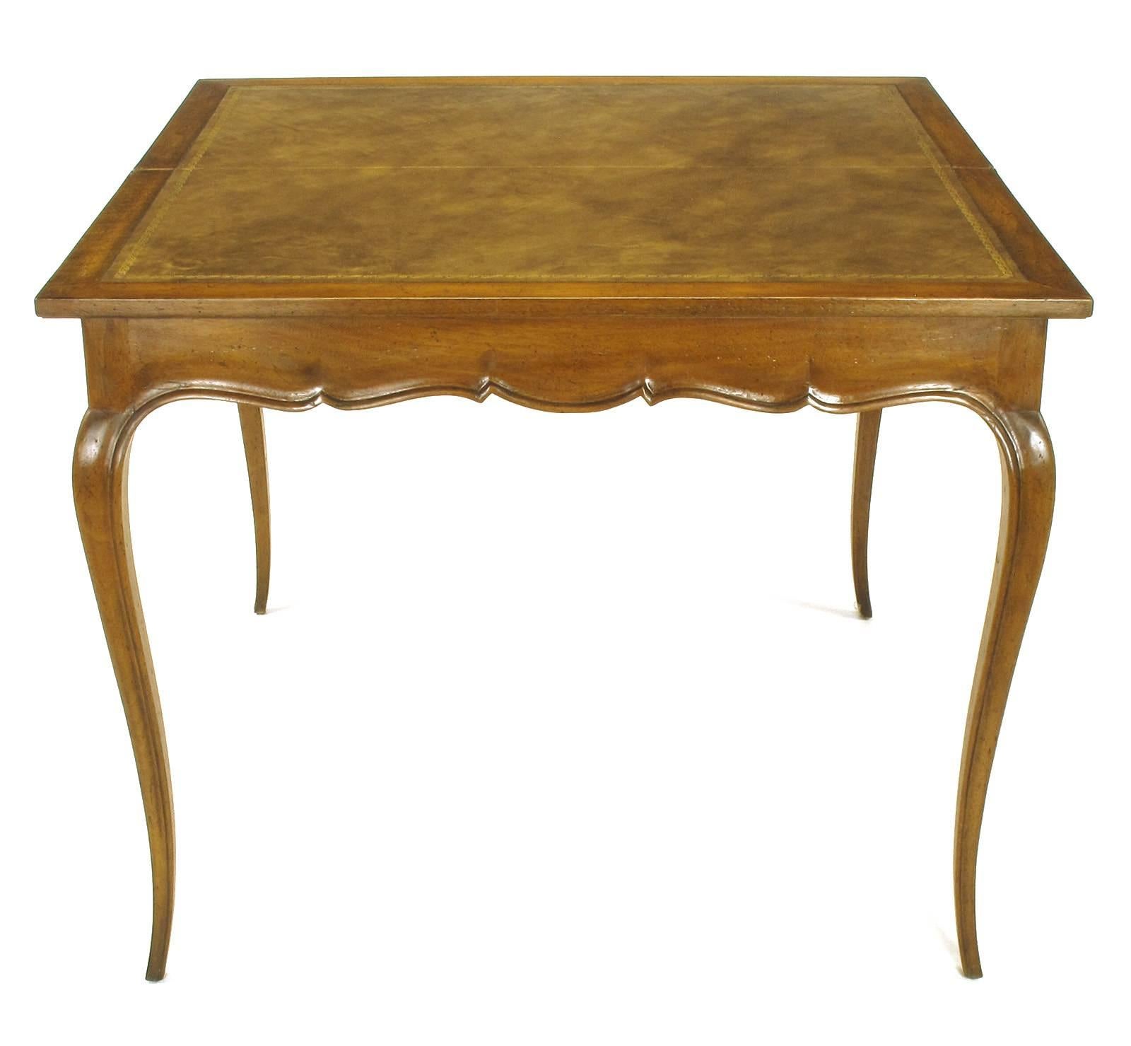 French cabriole leg flip-top games console table. Carved fruitwood with scalloped apron and finely tapered legs, brass hinges and sliding wood underside bracket for support when opened. Games table top is tooled and gold leafed leather. Aged finish
