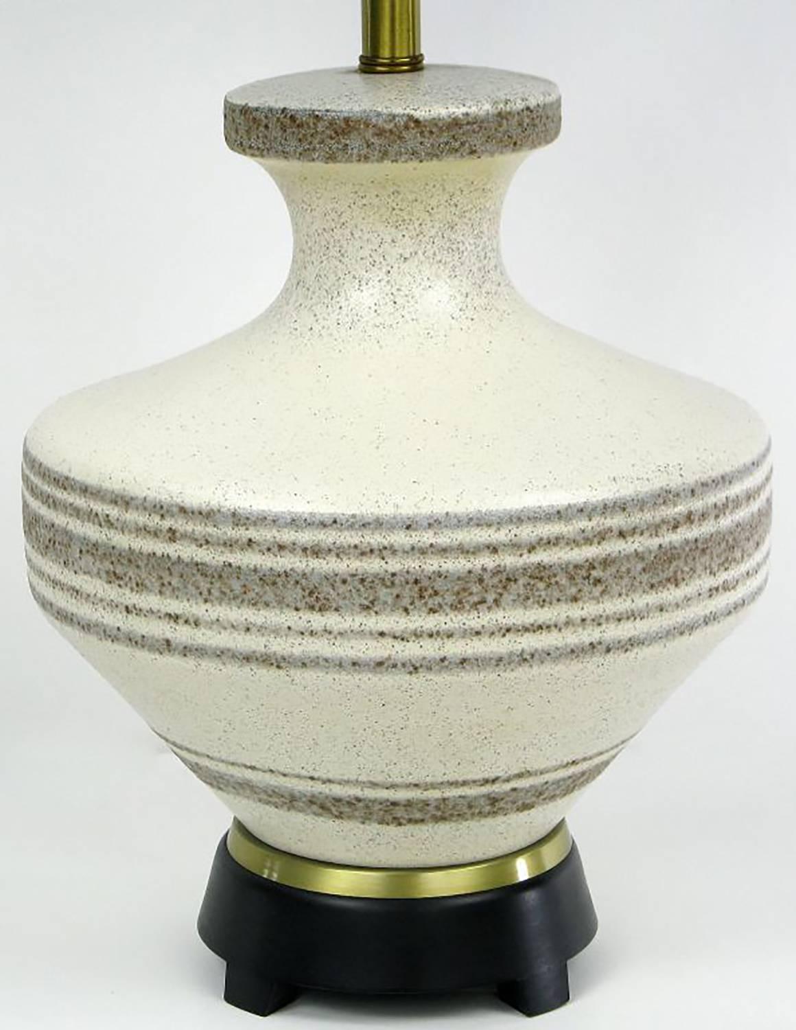 Hand thrown pottery table lamp attributed to Lightolier, with oriental urn shaped ceramic body glazed in speckled cream with taupe banding stripes. Three socket cluster which was a configuration most notably used by Lightolier. Black lacquered wood