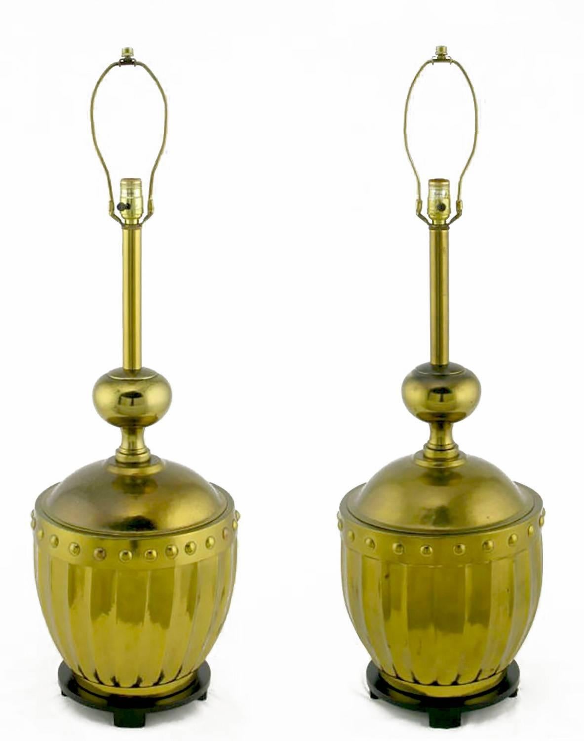 Large studded and fluted brass table lamps from the best years of Stiffel, the fine lamp maker. Black lacquered bases feature subtle chamfered feet. Surmounting the brass urns are brass post and ball columns. Sold sans shades.
