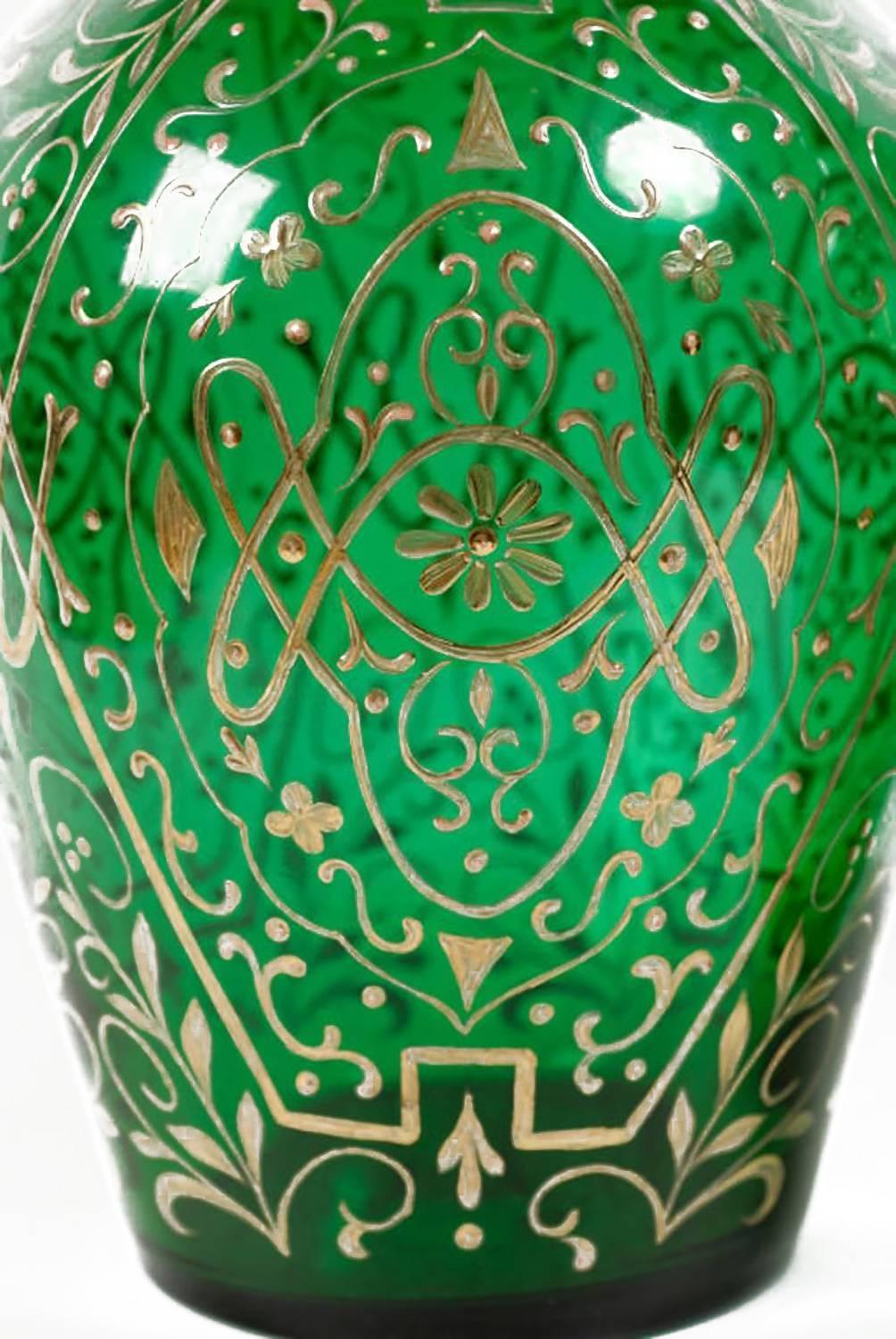 Tall and impressive, these huge green decanters have blown glass bodies with all-over gold-leaf foliate decoration. Equally impressive are the stunning stoppers, which are blown glass that was then cut into a form resembling obelisks. Believed to be