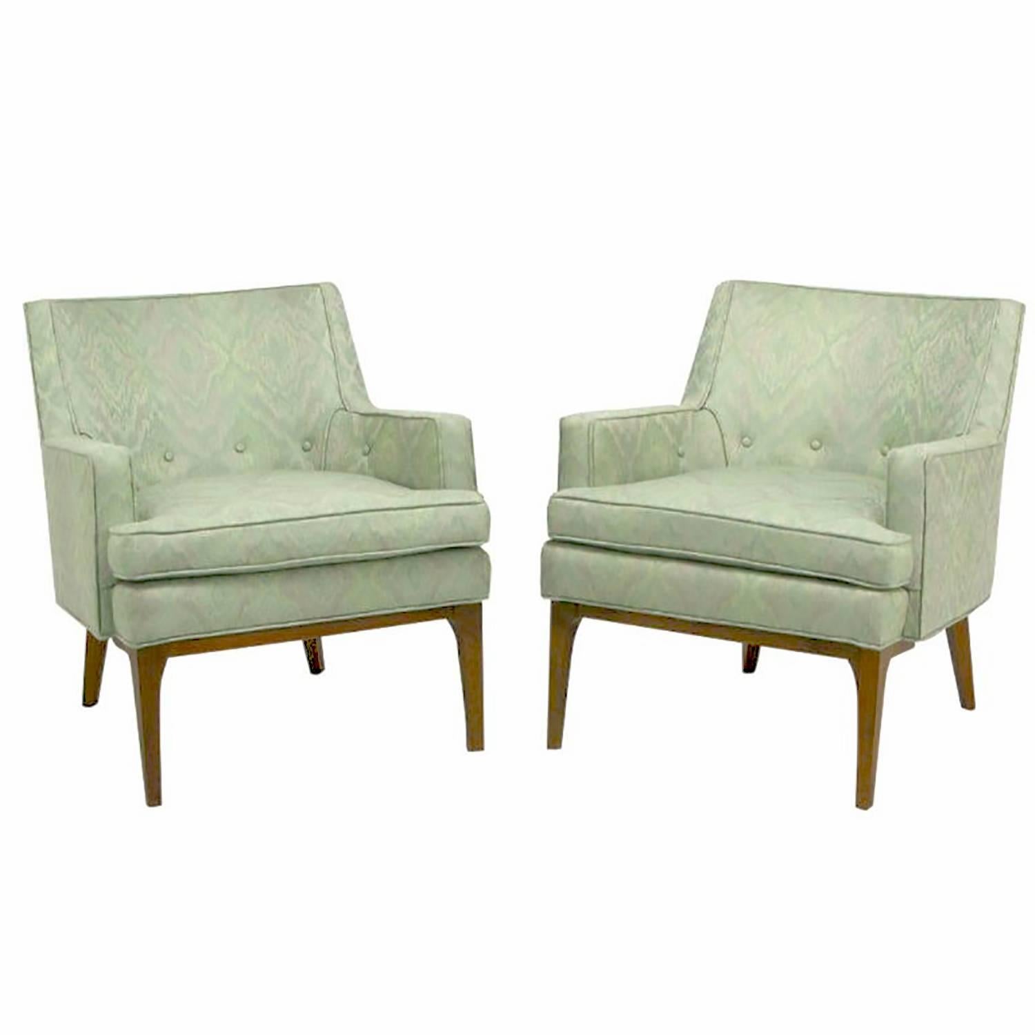 Clean lined pair of Classic club chairs in the manner of Jens Risom. Aquamarine and lavender Ikat patterned silk blend upholstery. Walnut wood legs with sculptural front apron and radiused corner legs. Loose seat cushion, and button accented back