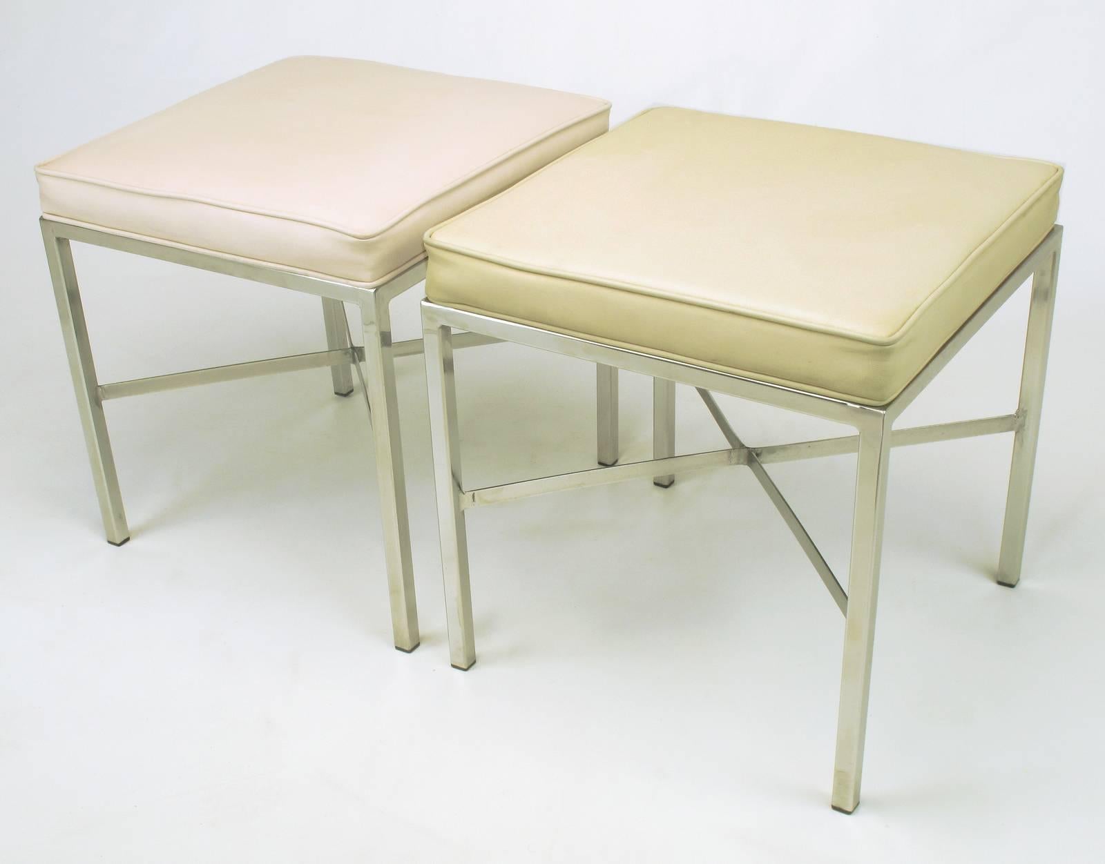 Pair of polished and flat steel X-stretcher ottomans or benches with complementary faux leather upholstery. One bench is covered in taupe and the other in a blush taupe. Welded X-stretchers are flat bar steel. Can be recovered COM for 100.00 per