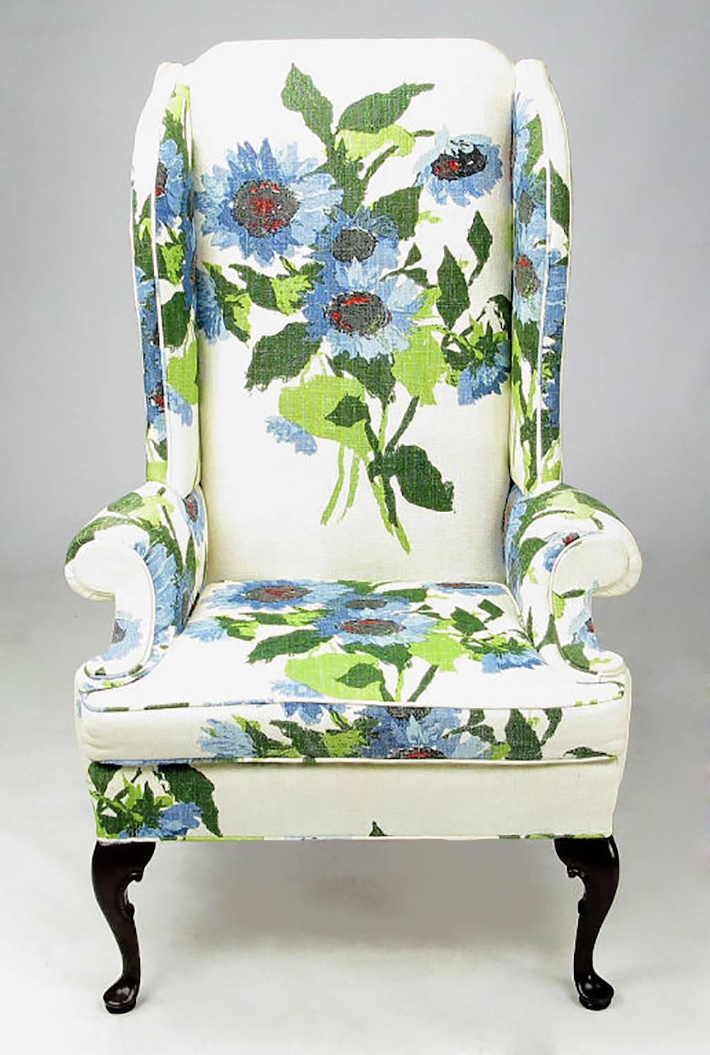 Elegantly modern pair of wingback club chairs from Hickory Chair Company. The oversized floral print linen is comprised of green, blue red and black flowers on a white ground. The front legs are cabriole carved mahogany and the mahogany back legs