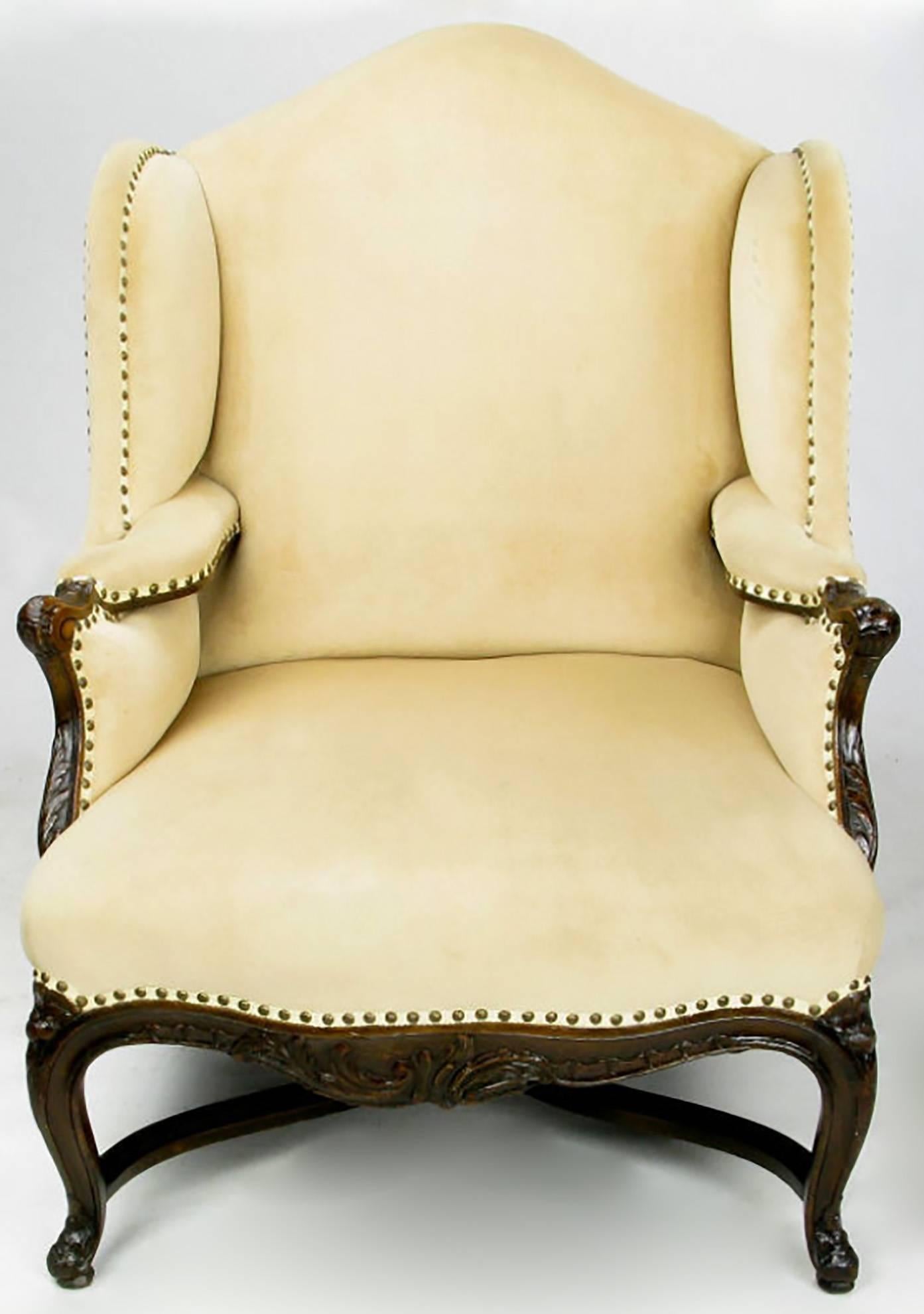 20th century recreation of a Classic Regence bergere with exaggerated wingback. The seat is quite comfortable and is almost wide enough for two. The camel velvet upholstery is set off by brass nailhead trim. Wonderfully carved wood arms and legs as