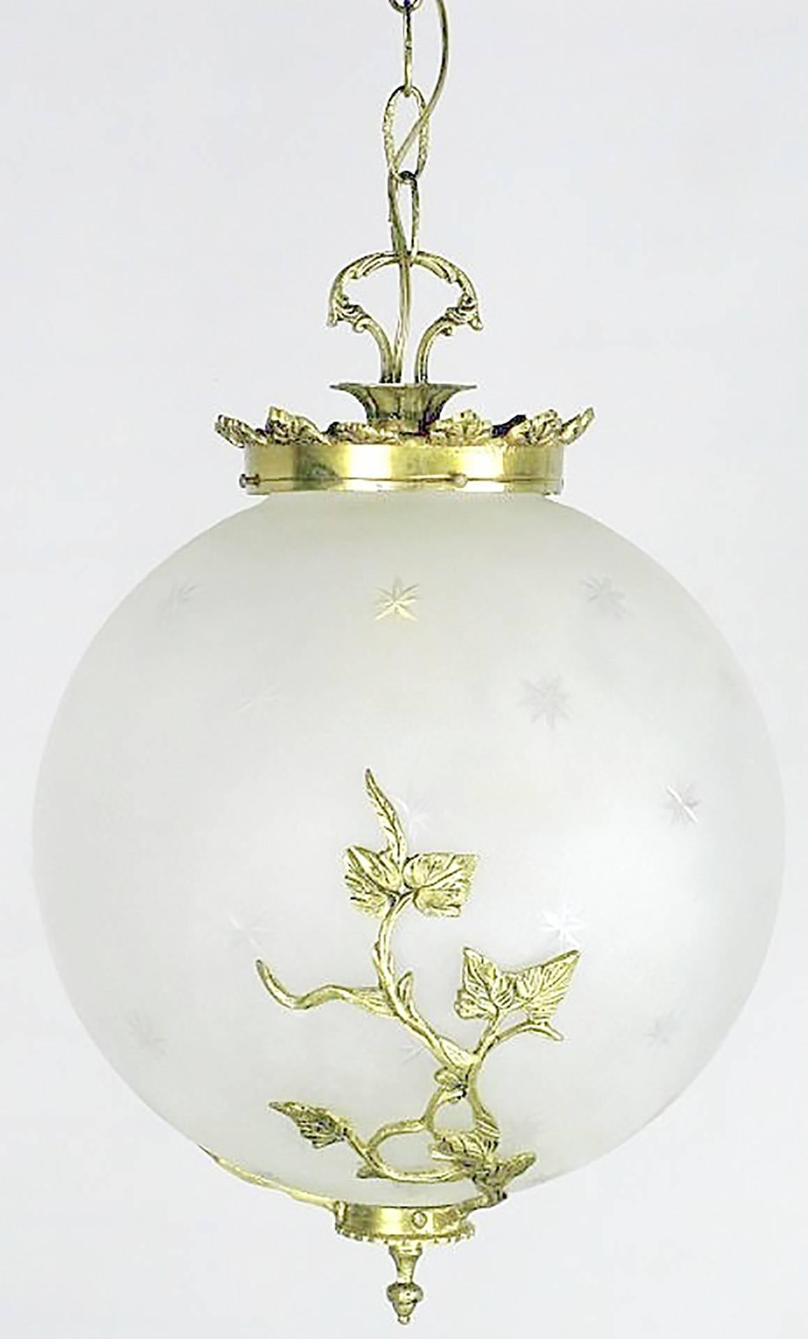 Alluring etched and frosted glass pendant with stars cut into the surface. Solid brass foliate details hug the lower hemisphere. Illuminated by a single internal bulb. Versatile pendant light that would function well as a petite chandelier over a