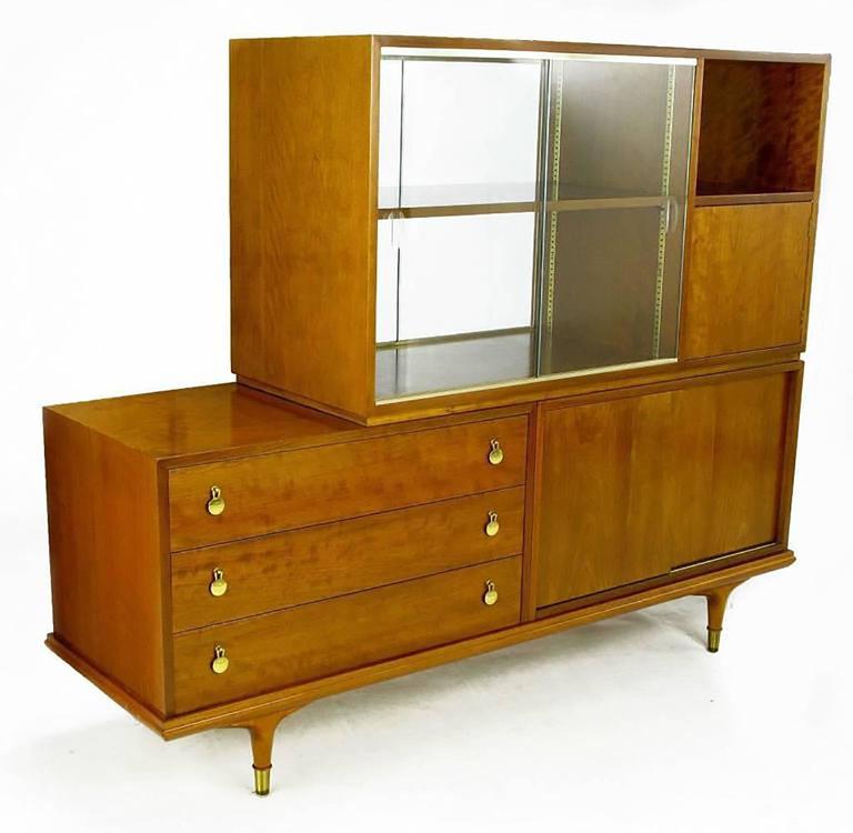 Modern cabinet or sideboard in figural walnut by Renzo Rutili for Johnson furniture. The top section features double sliding glass doors and a split opening with closed cabinet and one open. To the back there is a small open cabinet and the same
