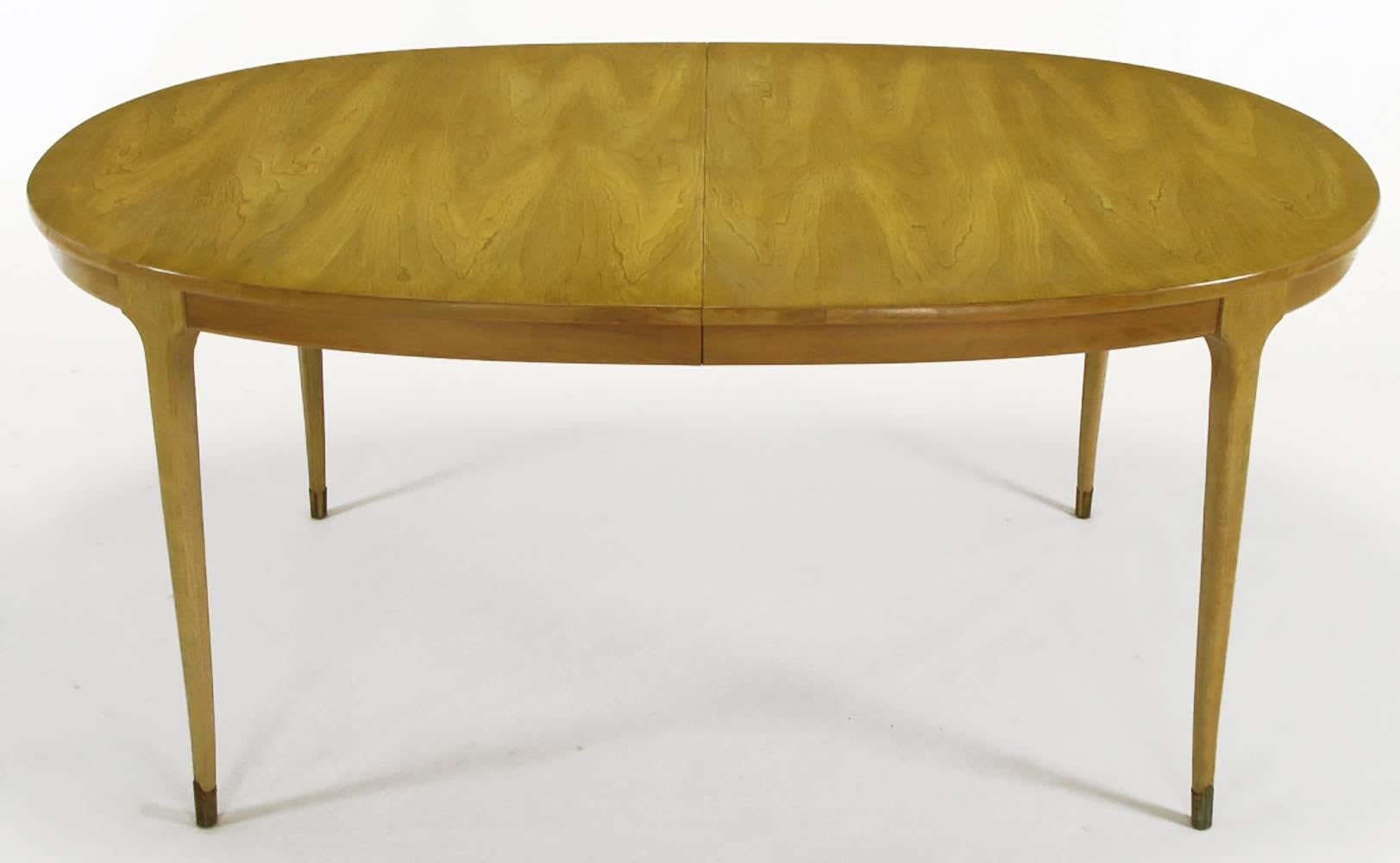 Bleached and figured walnut Classic, 1950s dining table in the manner of Harvey Probber. Clean tapered legs with slight saber curve and brass sabots. Beautifully figured wood grained top with two 16