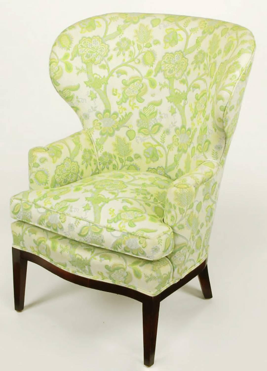 Uncommon wide wingback chair with an embroidered green, yellow and taupe linen upholstery. Simple clean line mahogany curved front apron and legs. A documented and very early Wormley design by Dunbar. 
