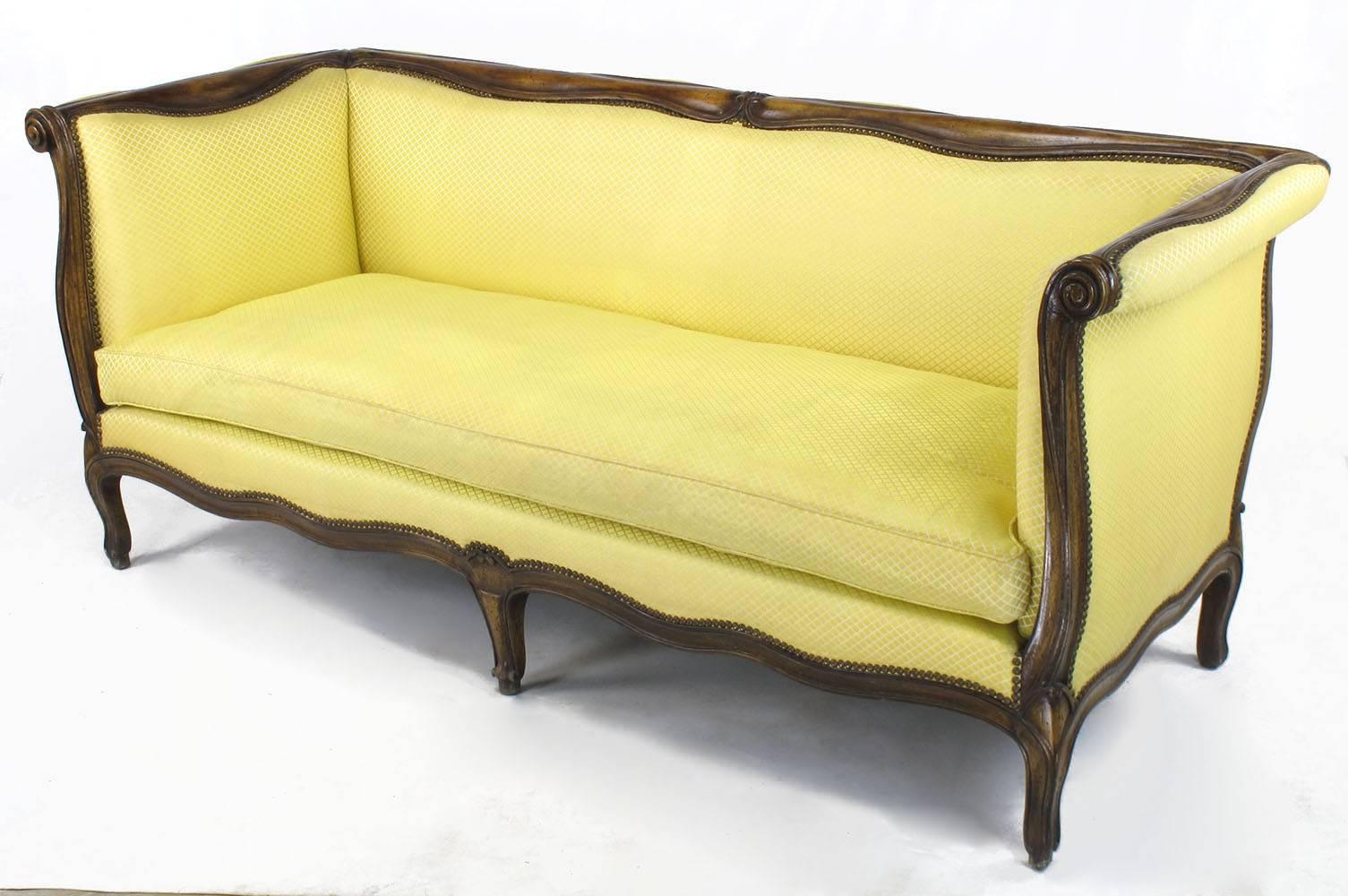 Yale Burge, reproduction de haute qualité d'un canapé à bras pairs de style Louis XV. Cadre en hêtre sculpté à la main, noyer vieilli et teinté, avec un coussin à assise simple rempli de duvet. Tapissé d'une soie jaune hachurée en bon état, à