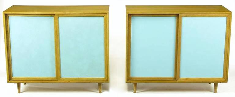 Rare pair of Harvey Probber two door cabinets with Tiffany blue leather covered recessed door panels. Bleached and toned mahogany casement, conical legs, door frames and shelves. One cabinet features three sliding shelves and two adjustable shelves,