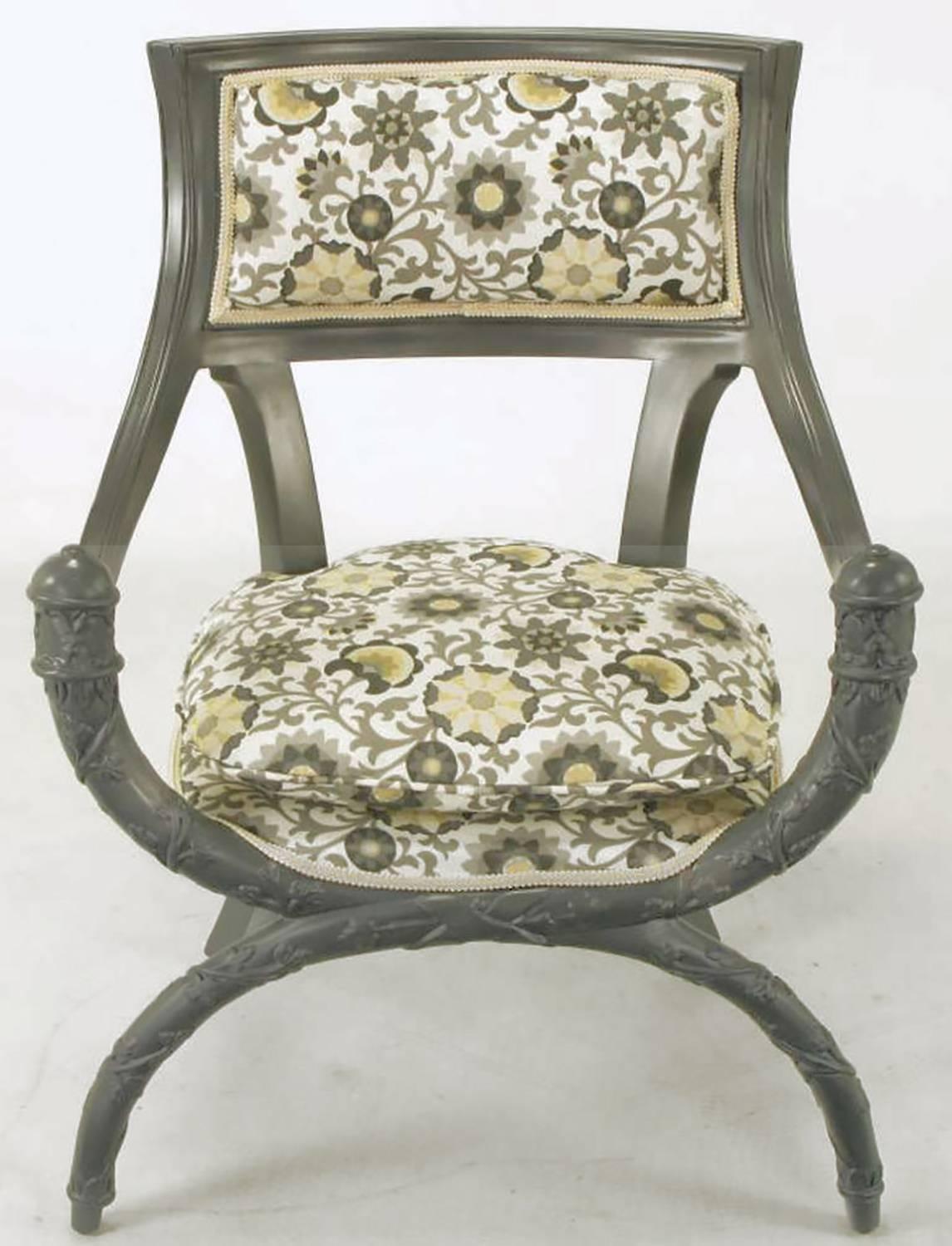 Pair of uncommon Curule front arm chairs in updated slate gray lacquer over wood. Seats and backs are upholstered in a modern gray and saffron print on white cotton. Deep sloped arms and rear saber legs complement the rounded seat and carved vine