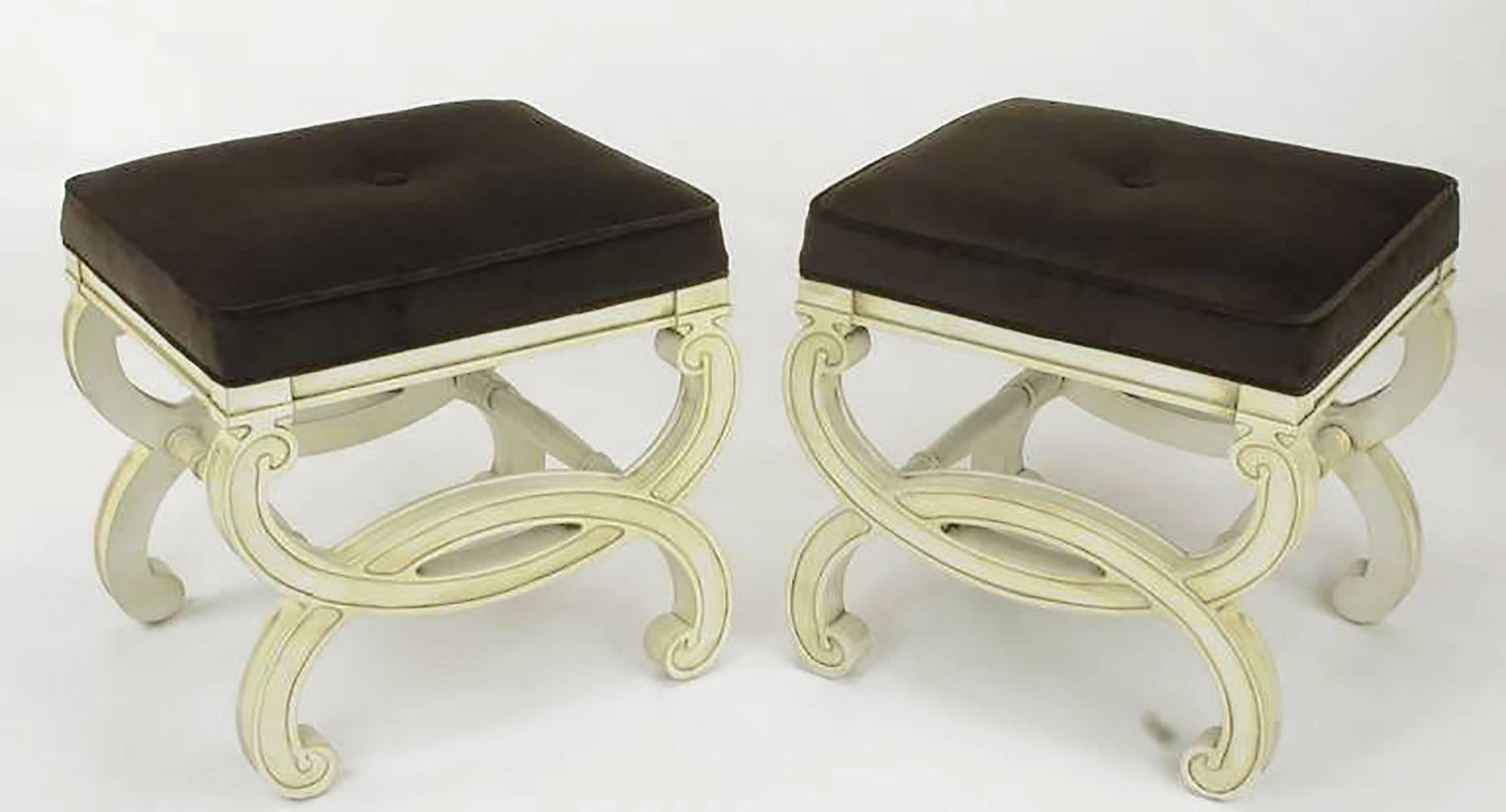 Restored pair of Regency style benches with fresh ivory lacquer and umber glaze. Seats have been recovered in a sable velvet upholstery. Single button tufted. Unique in that the legs are carved to look like interlocking cuffs with turned dowel