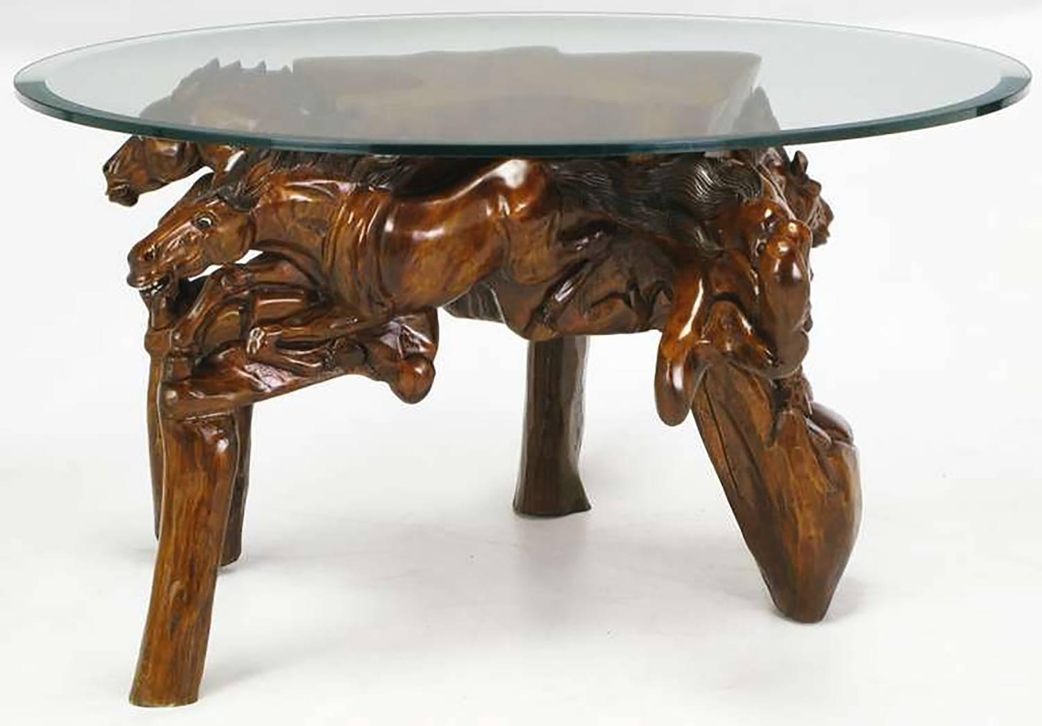 Expertly crafted work of art, this coffee table is hand-carved from wood, stained and burnished, then polished. Galloping horses appear to be coming from the centre of the table base. Legs are carved to resemble wood posts. Glass top is beveled and