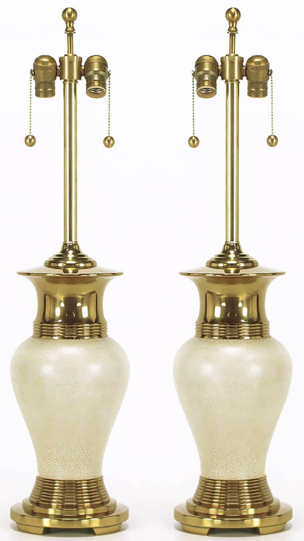 Pair of modern table lamps with heavy brass open footed basses and flanged vase form tops. The vase form body is ivory crackle glaze over brass. Brass stem and dual socket cluster with brass ball pull chains. Sold sans shades.