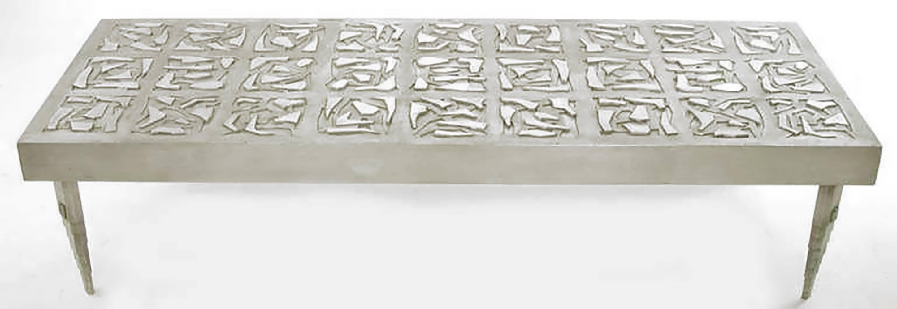 Custom aluminium studio coffee table that measures over six feet in length. Top composed of 27 square relief sections that are thematically similar, but are each unique. Four canted aluminum legs are inverse ziggurat form, with artist's