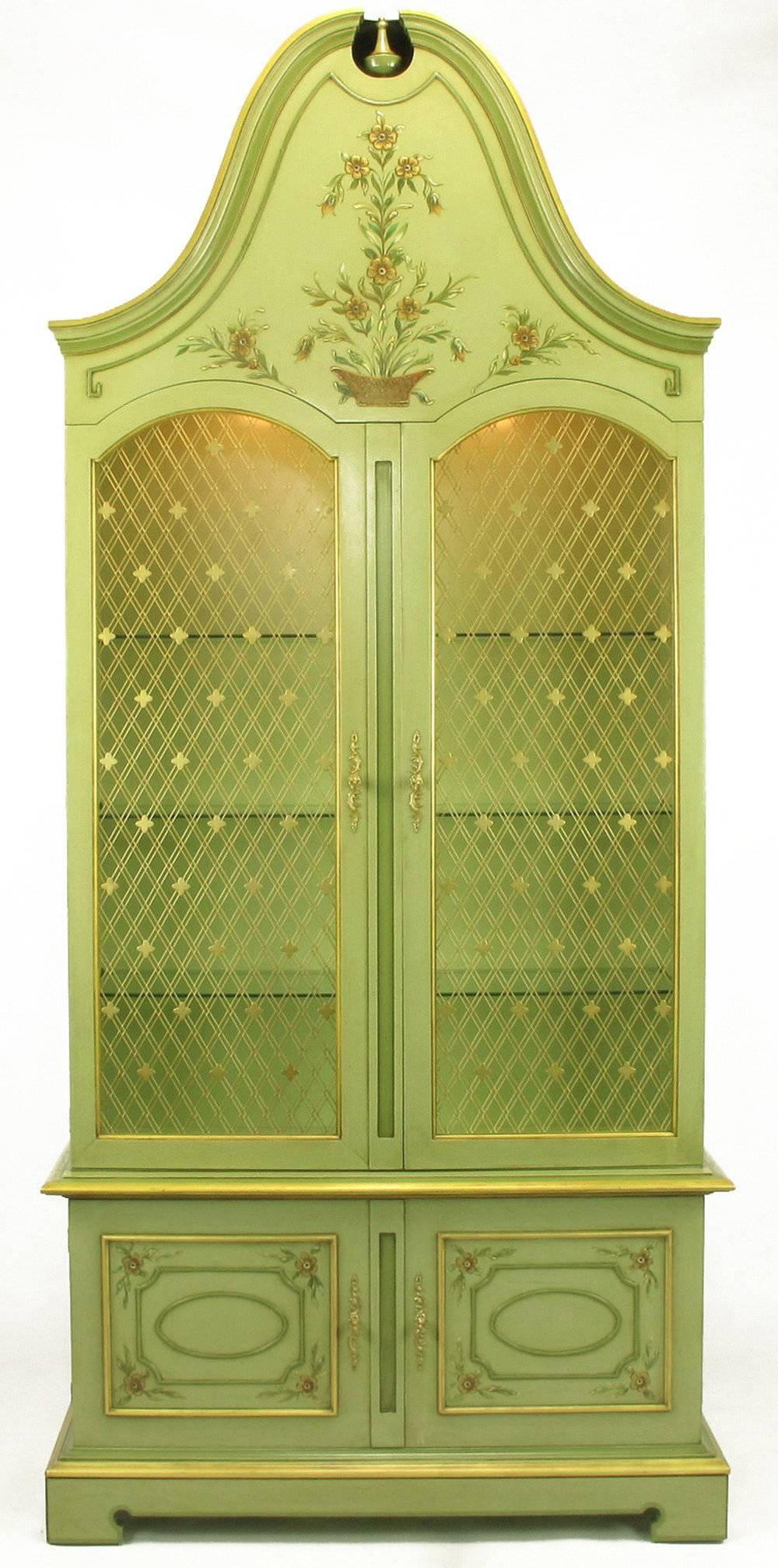 Uncommon John Widdicomb hand-painted French Regency display cabinets in exaggerated fanciful form. Gilt cross hatch wire insert doors with quatrefoil detail. Illuminated interiors, glass shelves and gilt details. Hand-painted floral detailing to