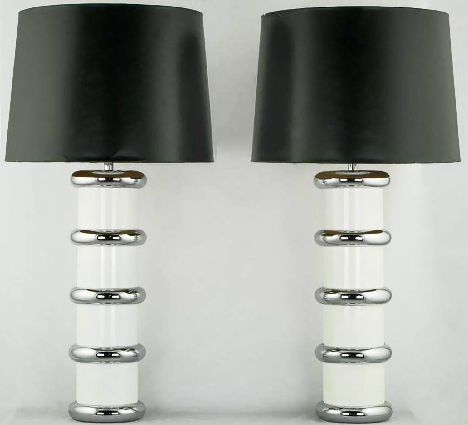 Pair of tubular form table lamps in white enameled steel with chromed steel cuff rings, stem, socket and harp. From the mutual sunset lamp company; a now defunct lamp company that featured designs by Gilbert Rhode, among others. Sold sans shades.