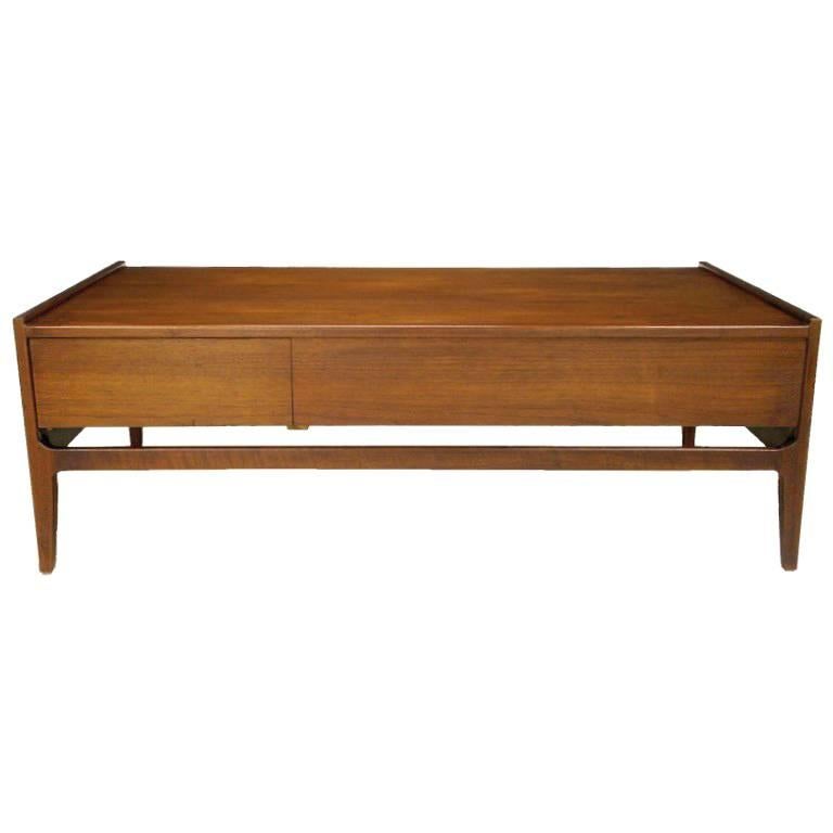 This clean lined coffee table by Richard Thompson reflects California Modern at its best. Constructed of walnut and oak, and finished in walnut veneer, the table features a concealed flush drawer for storage.