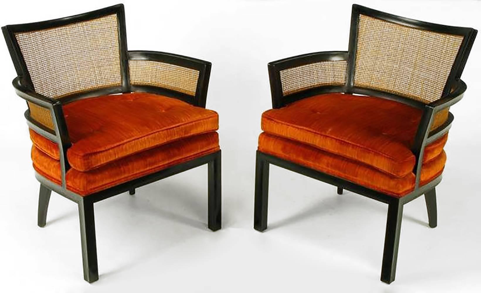 Pair of ebonized mahogany and cane arm chairs by Baker Furniture. Stacked and loose seat cushion is upholstered in a button tufted persimmon velvet. Most likely a Michael Taylor or Winsor White design.