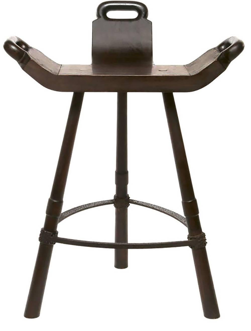 Pair of tripod-base bar stools with seats inspired by Primitive birthing chairs. Hand-hammered iron stretchers with Brutalist texture, and walnut wood legs and seats. Seats have integral back support and hand grips.