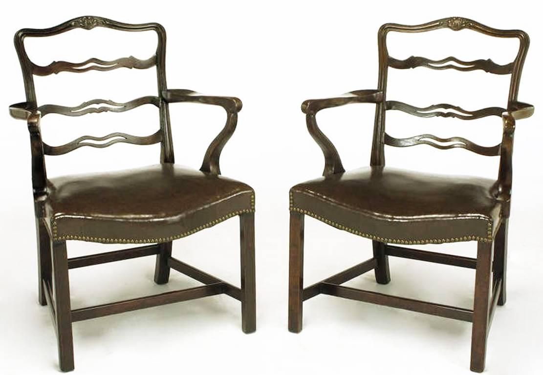 Finely reproduced pair of walnut George III armchairs. Ribbon backs with sinuous arms and a brown leather-like bow front seat with brass nailhead tacks. Four part stretcher with beaded legs. American made.

