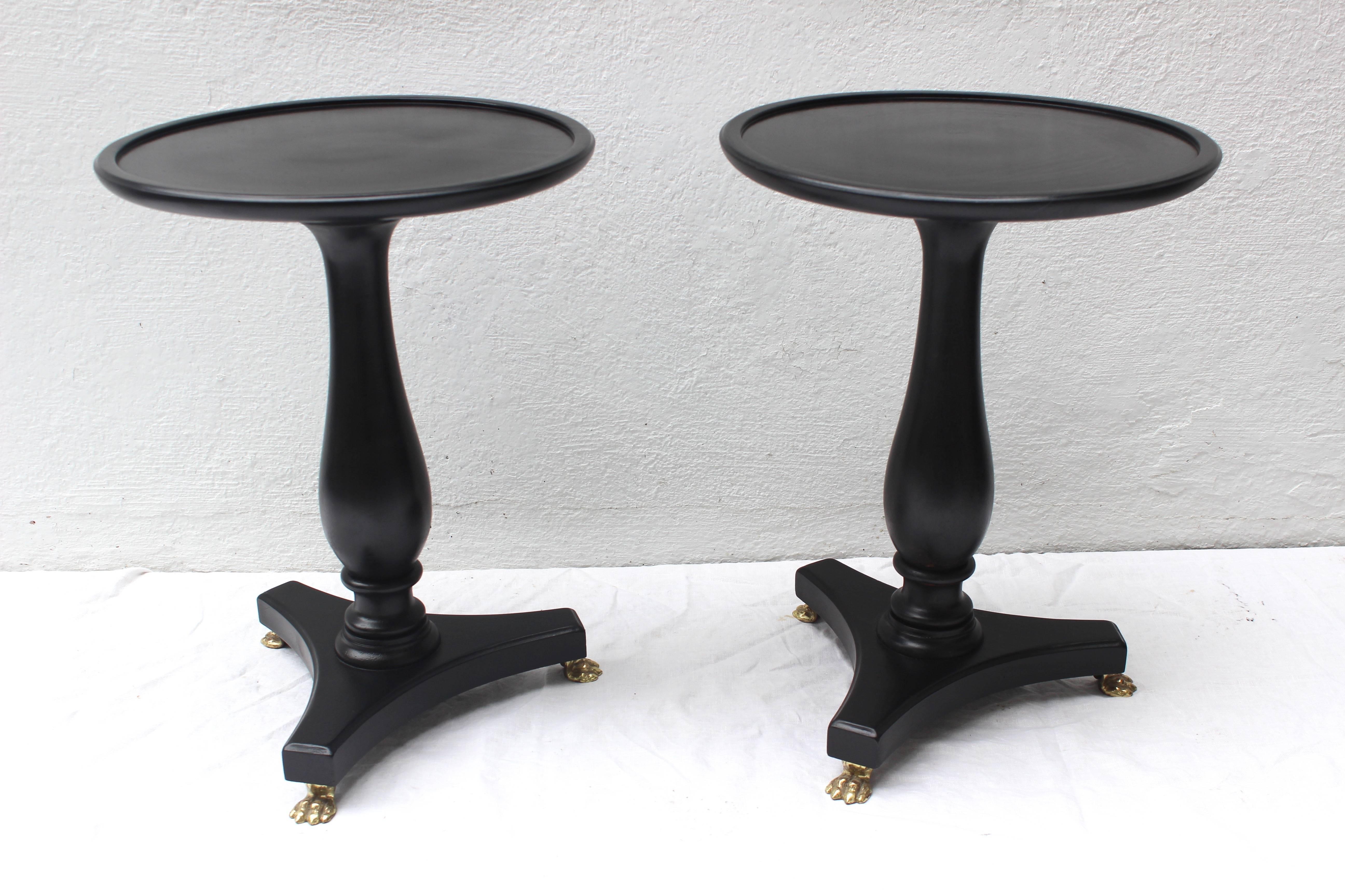 Pair of ebonized occasional pedestal tables with brass feet.