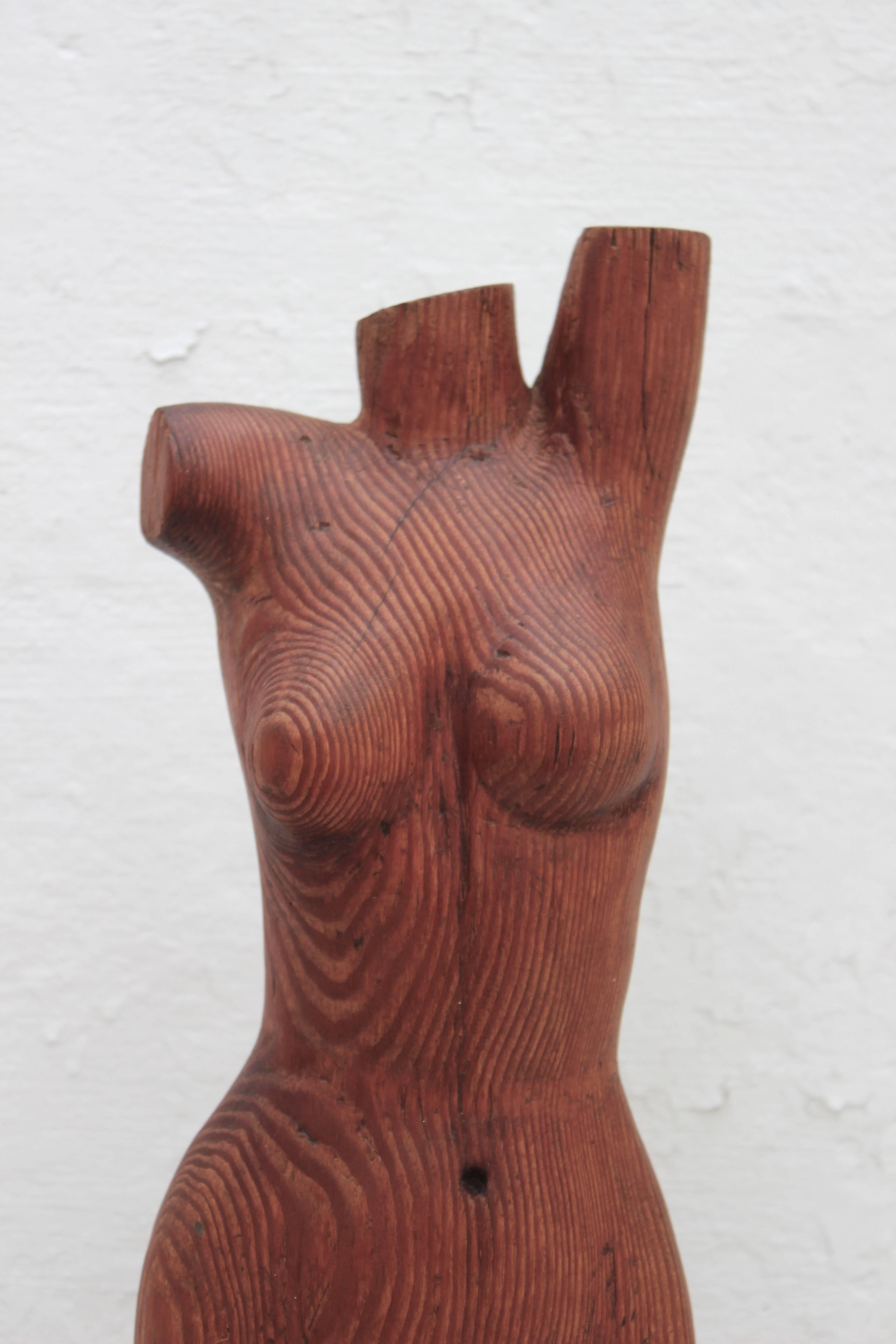 Carved wood figural sculpture of nude female's torso mounted on black laminate wood block plinth.