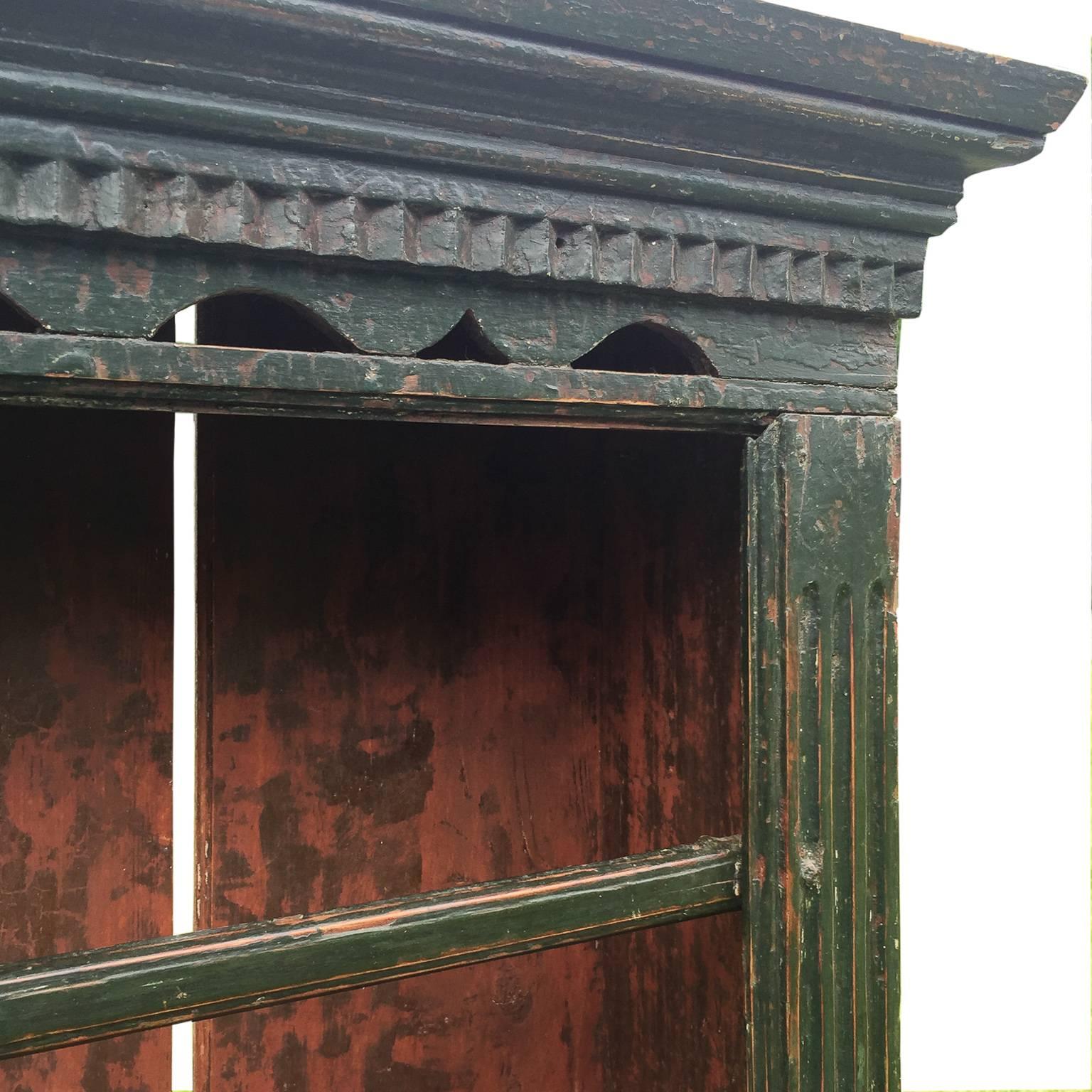This charming cupboard from Limerick, Ireland with traces of the original green paint was made to either hang on a wall or sit comfortably on a tabletop. It has a bottom shelf and three other shelves each with a plate rail. The cornice has very nice