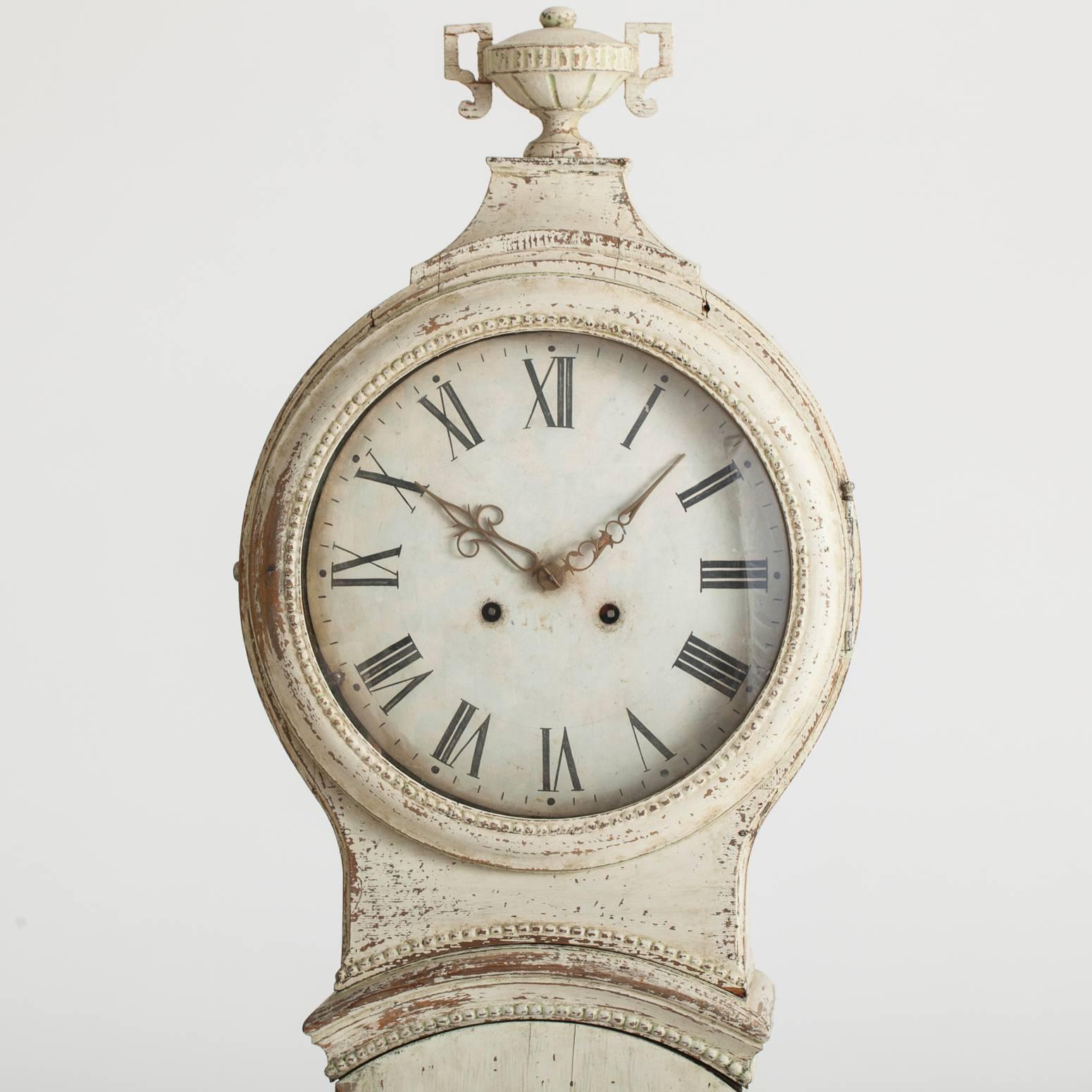 At 80 inches high this charming clock is great for a house with a low ceiling, yet has all the elements one could hope for, lovely carvings and a Classic urn on the top. The face is surrounded by delicate beaded molding, and the traces of white