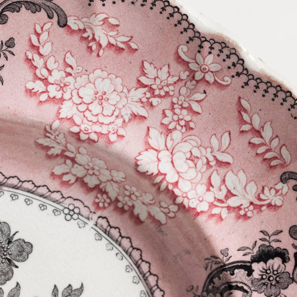 An unusual color combination makes this pink and black romantic transferware platter a very special one. A pink border with black medallions of oriental scenes surrounds a sumptuous bouquet of flowers. This piece is unmarked but dates to around 1840