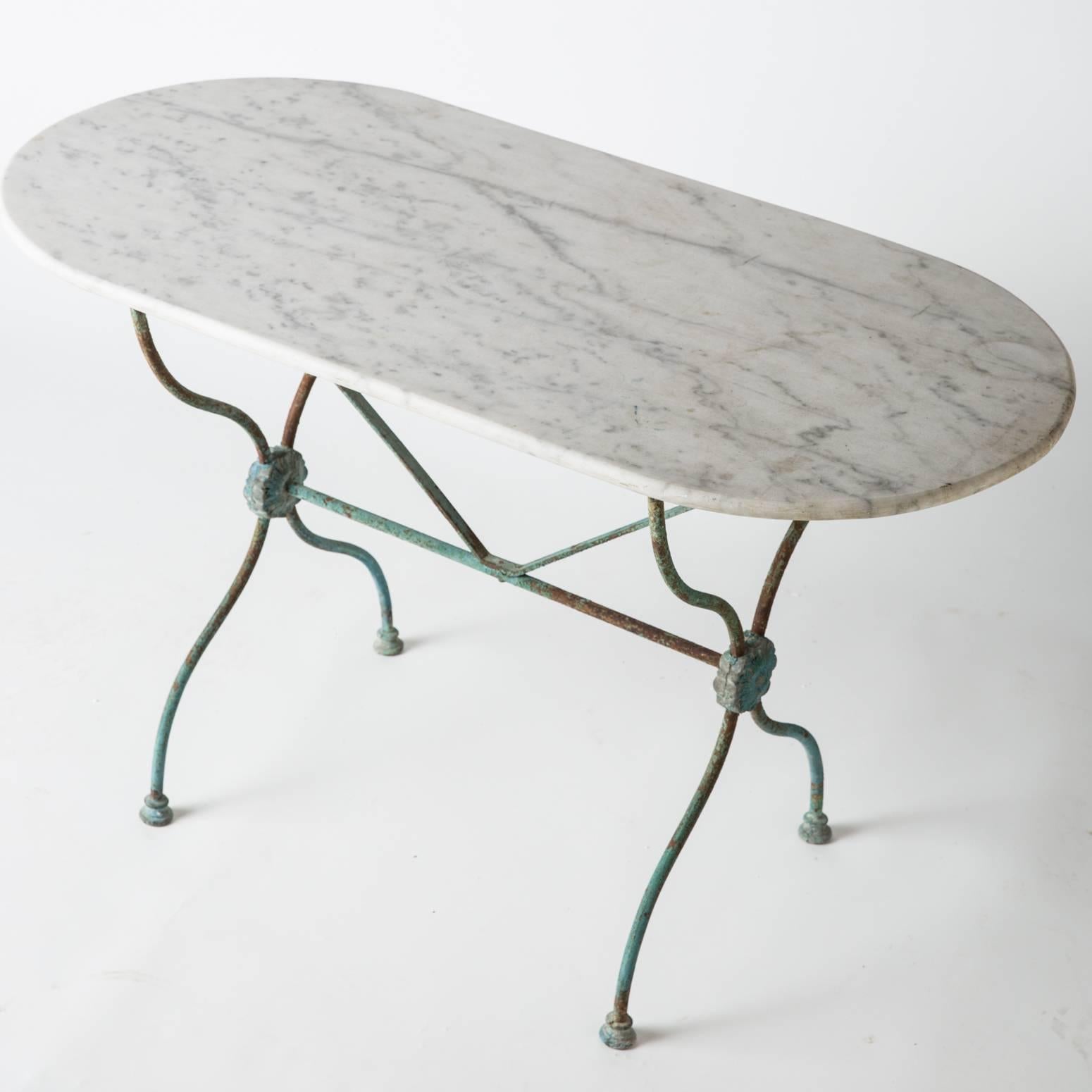 This table features a great wrought iron base, with side medallions ending in early pad feet. The blue/green base still retains the beautiful original paint. The antique oval marble top is in perfect condition.

Measures: 28” high
47” wide
23.5”