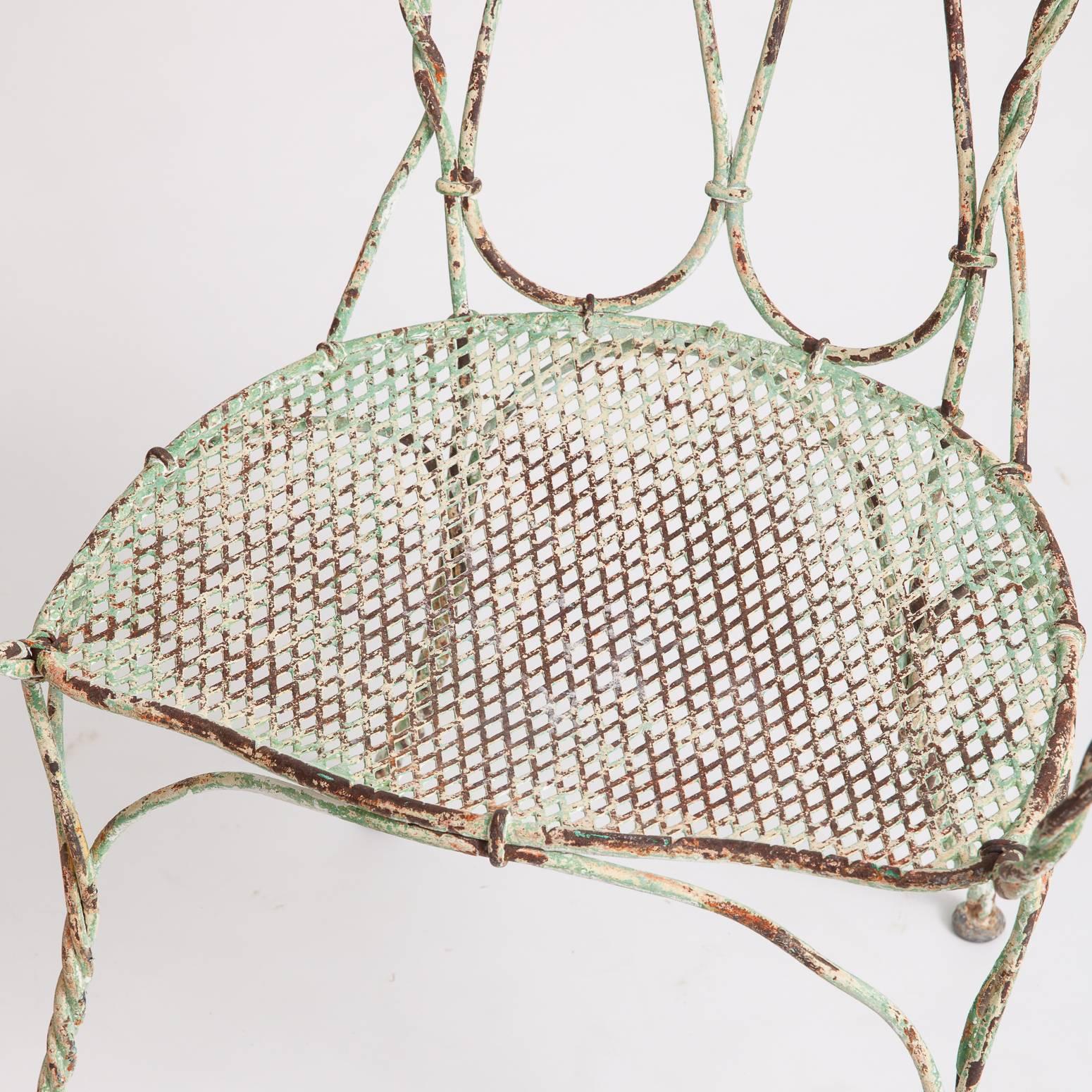 This pair of very early and rare French wrought iron garden armchairs have braided rope construction on the back and legs and mesh seats which are in very good condition. The slightly slanted backs allow for very comfortable seating. The light green