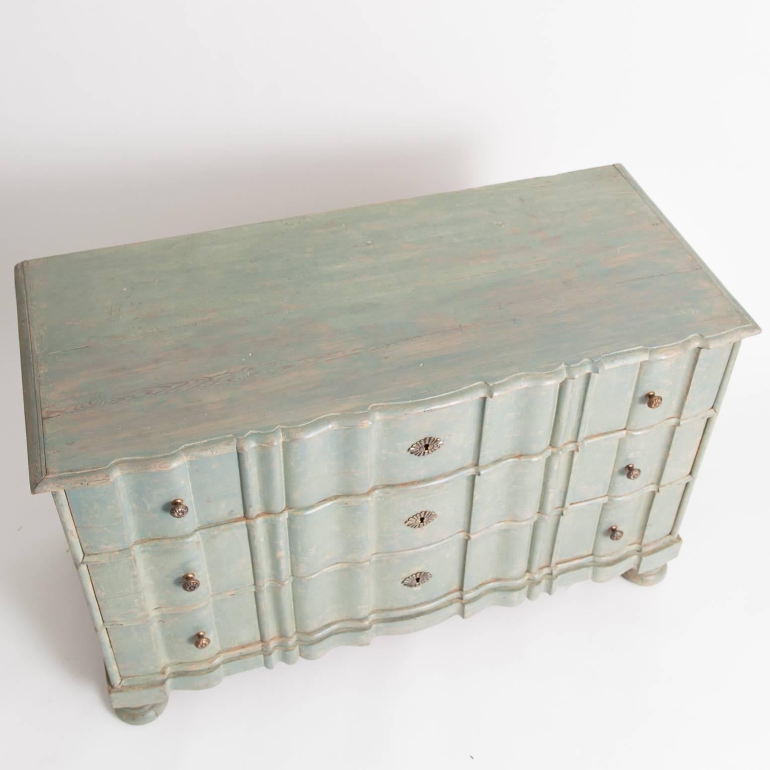 This elegant Swedish Baroque chest has a beautiful proportion and ball feet. Brass escutcheons and knobs adorn the serpentine front. The pale green paint surface is original. This piece dates to 1750.