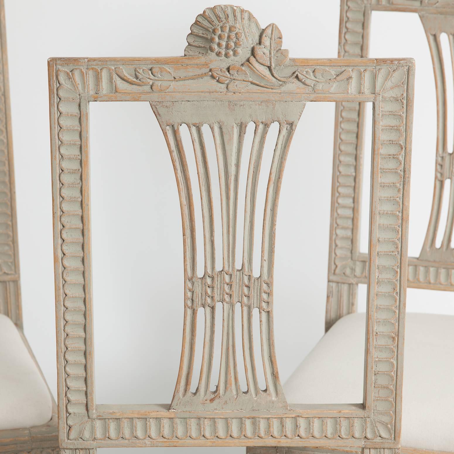 This set of four beautifully detailed chairs bear the fruit and flower carvings of the hops plant, the signature of the Lindome furniture maker's guild in Sweden. The wooden backs with slats forming a fan shape, are framed by intricately carved
