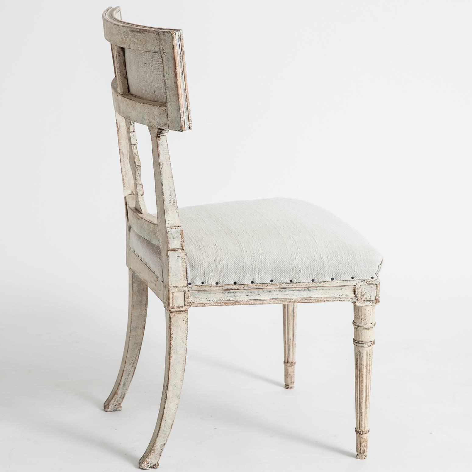 This lovely set of six dining chairs belonging to the late Gustavian period have open backs with reeded sides. Triangular central medallions lead to curved and upholstered backs. The reeded front legs are tapered and the back legs end in an elegant