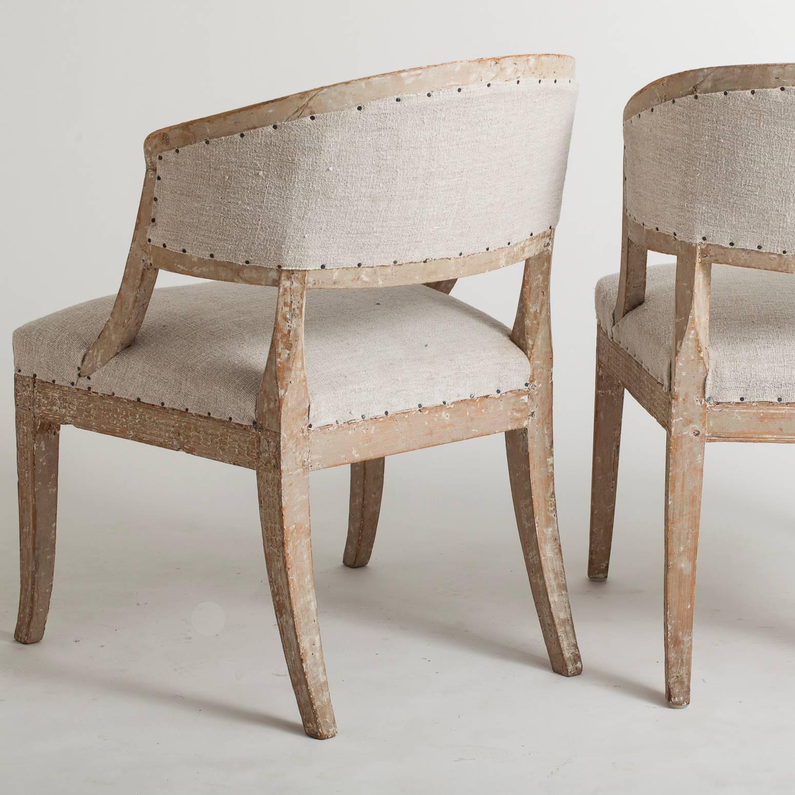 This pair of barrel back chairs have many elements that make them truly unusual. The pale paint surface is original and delicate carving on the back and legs are beautifully executed. A subtle woman's face carved at the end of arm is very special