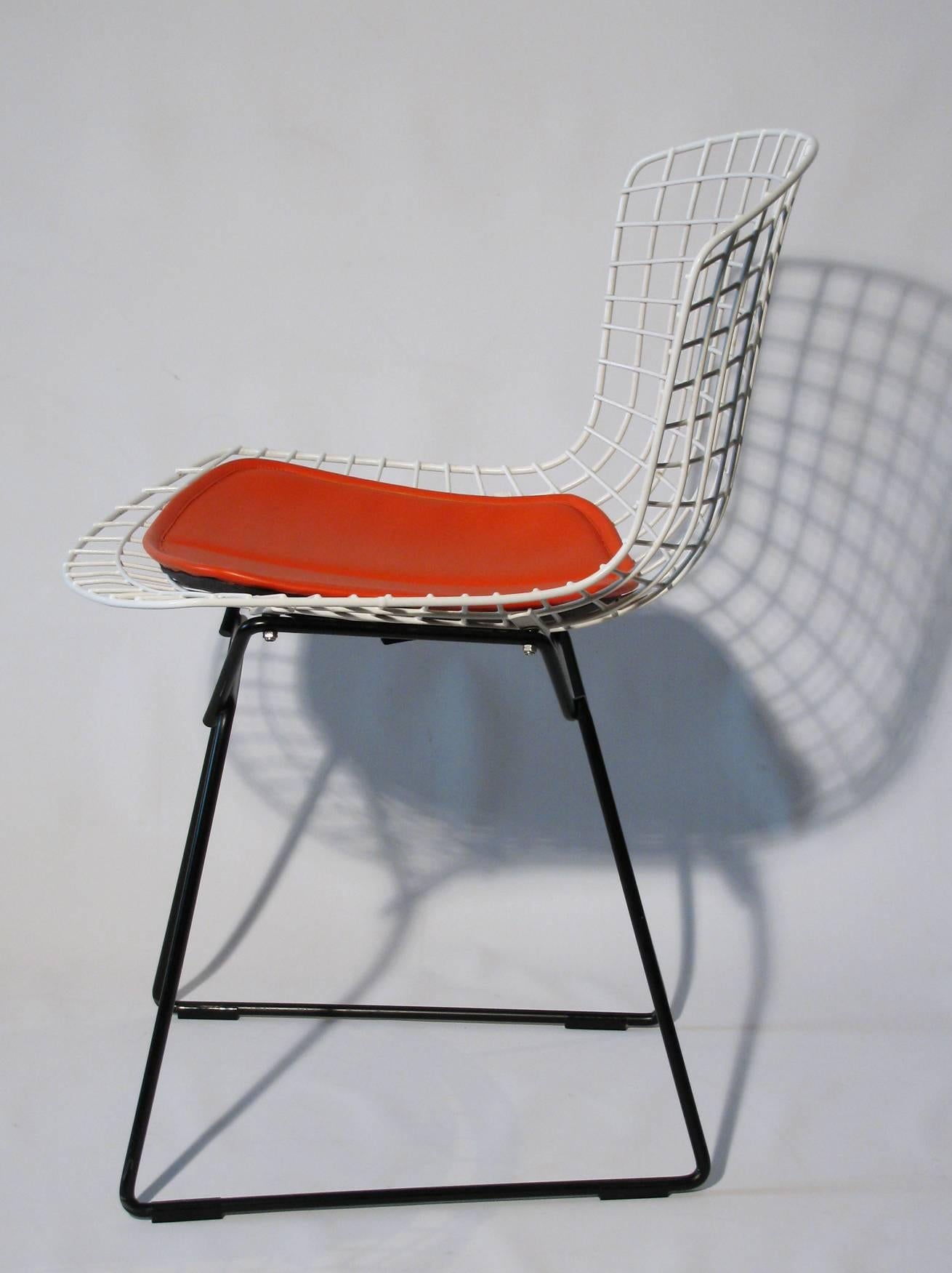 A chic pair of side chairs by Harry Bertoia (Italian/ American, 1915-1978) for Knoll. White enamel wire seat with black base; each having an orange padded seat.