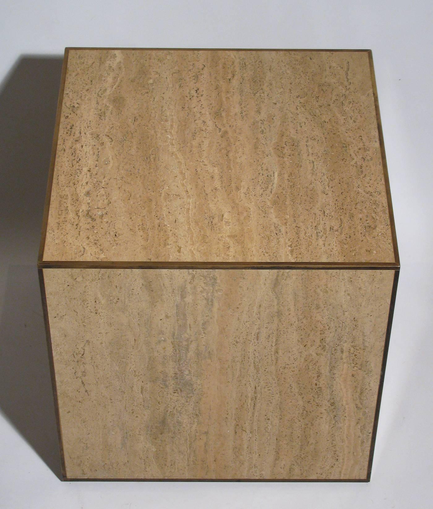 A travertine cube table with brass edge trim on all sides, on a slight stepped base. Brass trim has a wonderful simple patina.